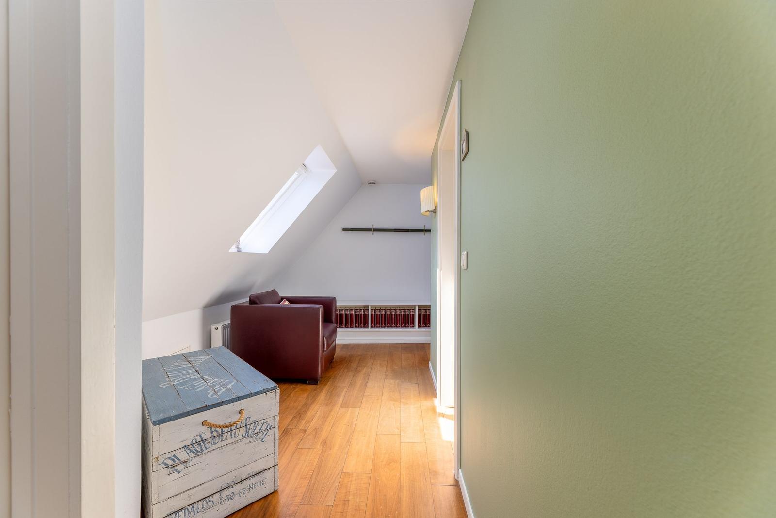 Wohnbereich mit Ledersofa, Holzboden und großem Fenster.