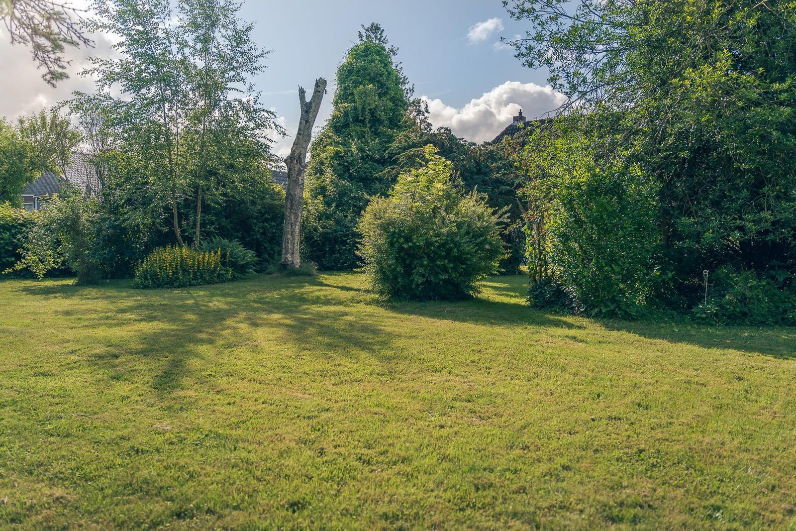 Weiße Hütte mit Garten und Eingangstür. Fenster mit Vorhang.