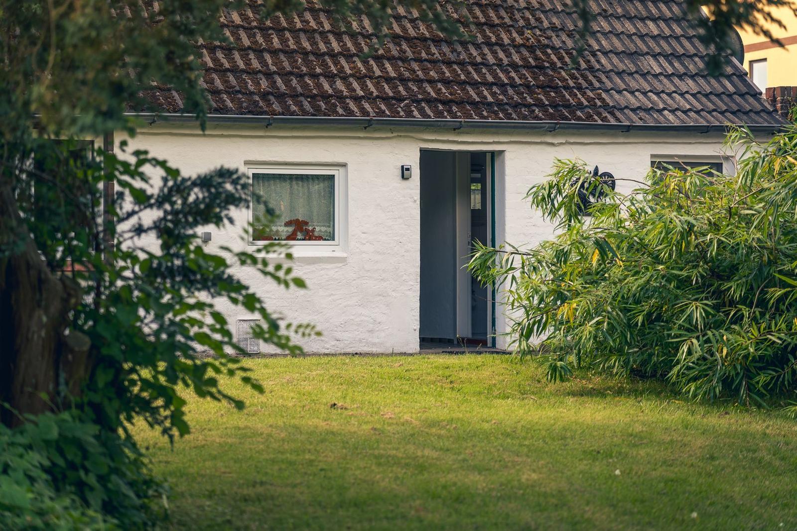 Weiß verputzte Ferienwohnung mit grüner Tür und Wanddekoration.