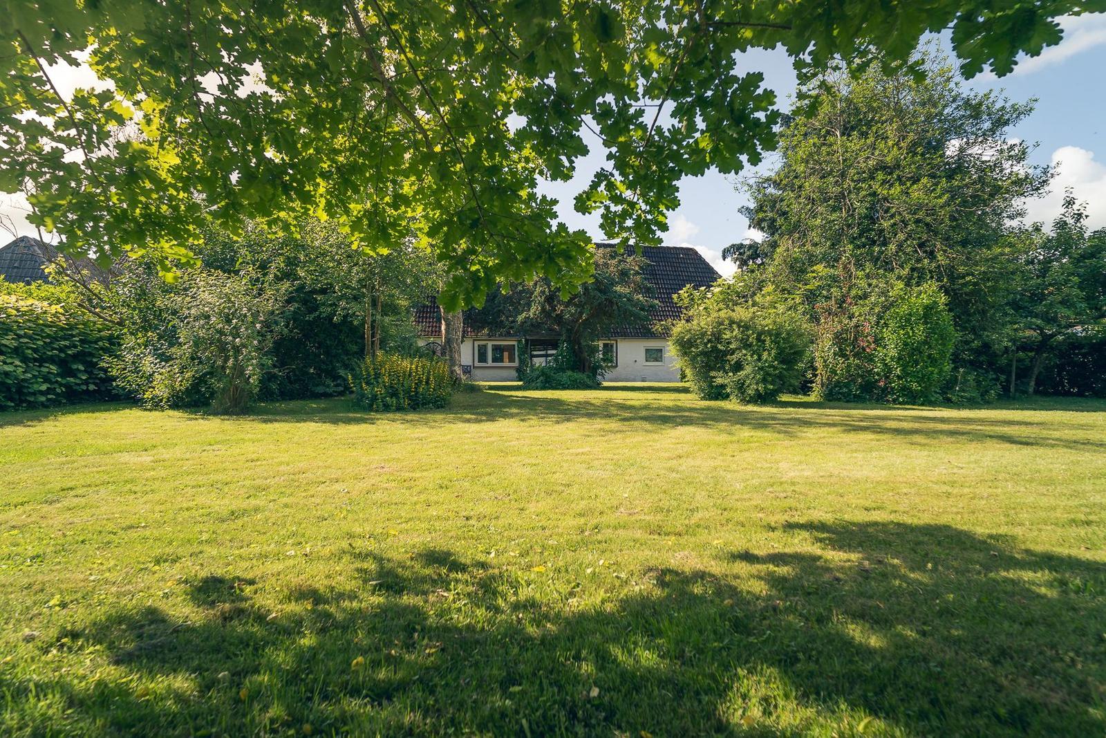 Hinterhof mit Tisch und Stühlen, umgeben von Steinplatten und Pflanzen.