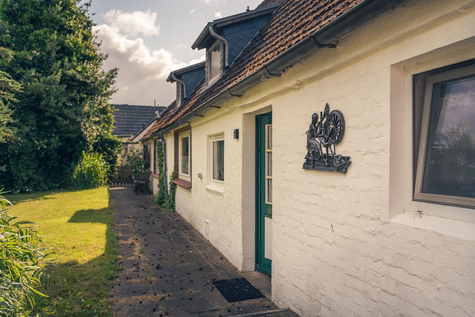Eine Bank mit Blumenmotiv steht vor einem Haus mit weißen Wänden und Kletterpflanzen.
