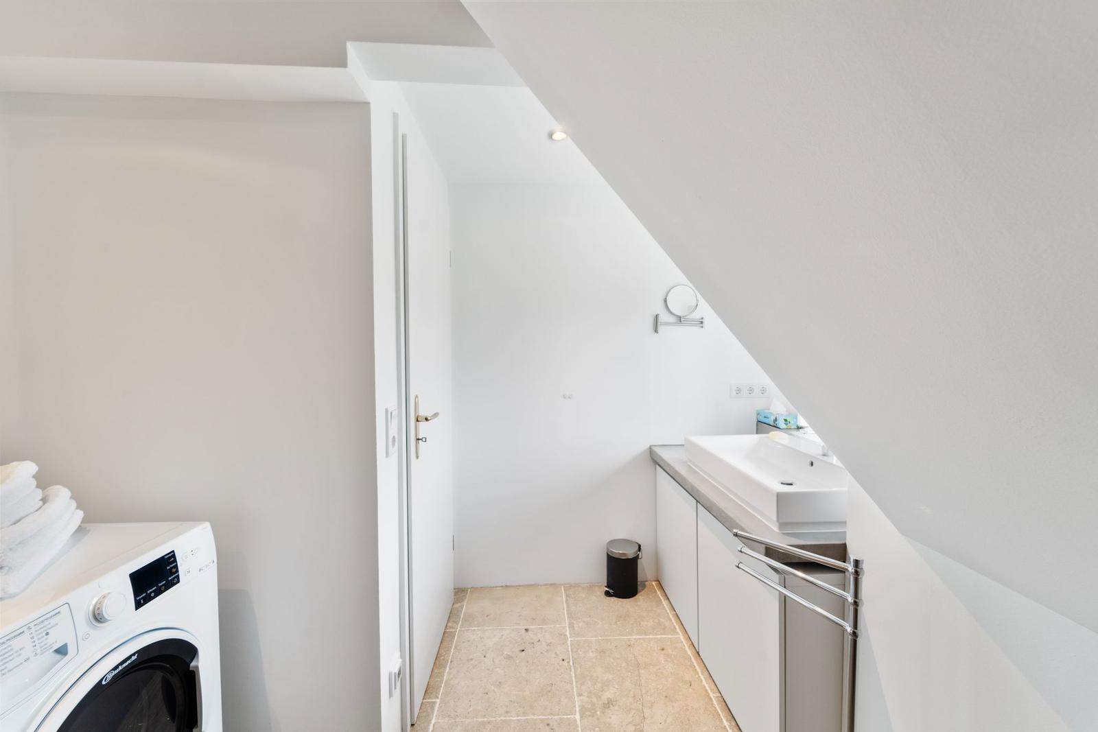 Badezimmer mit Waschmaschine, Spiegel und Fenster