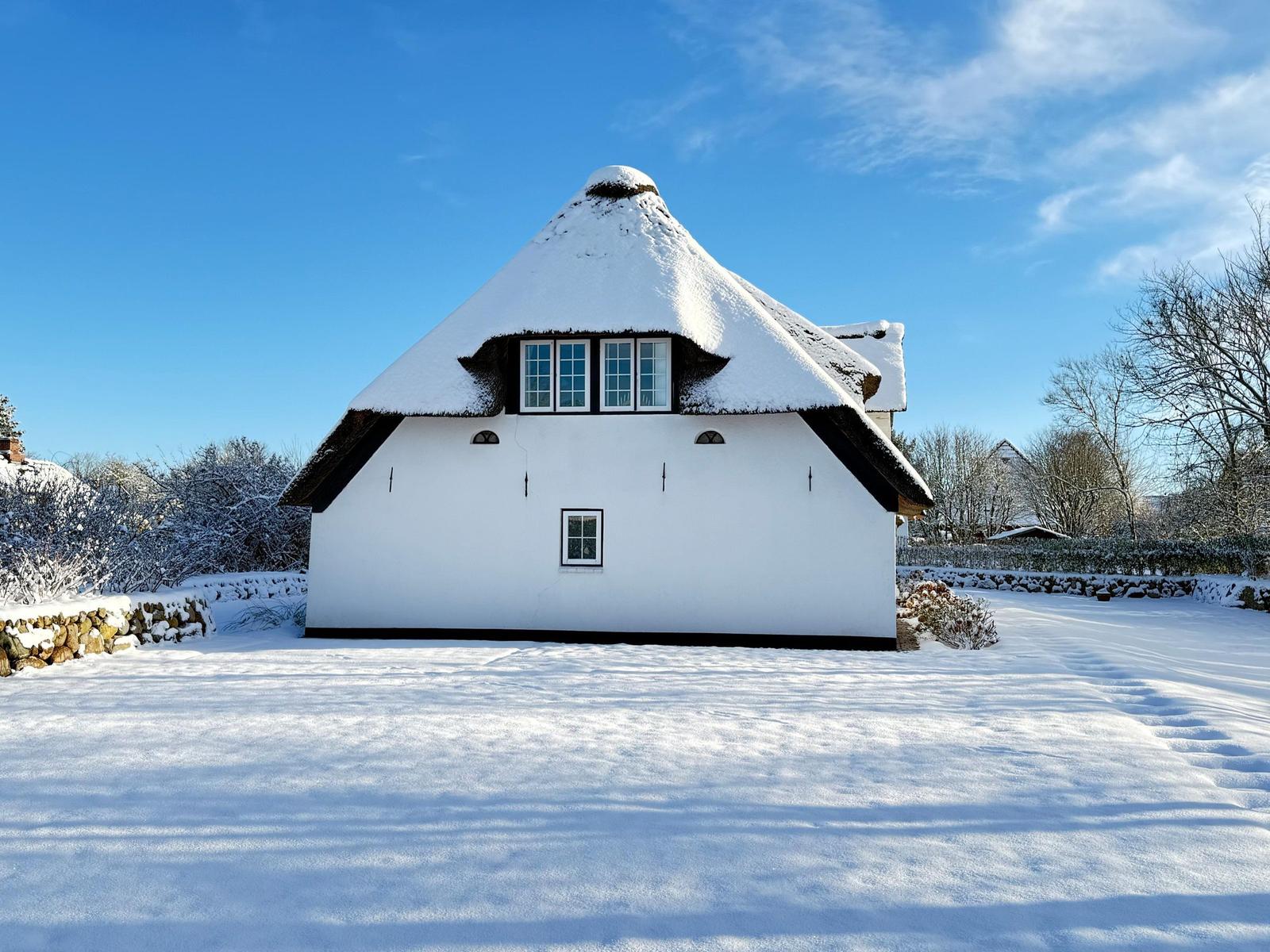 Schneebedecktes Fachwerkhaus mit Dach und Fenstern.