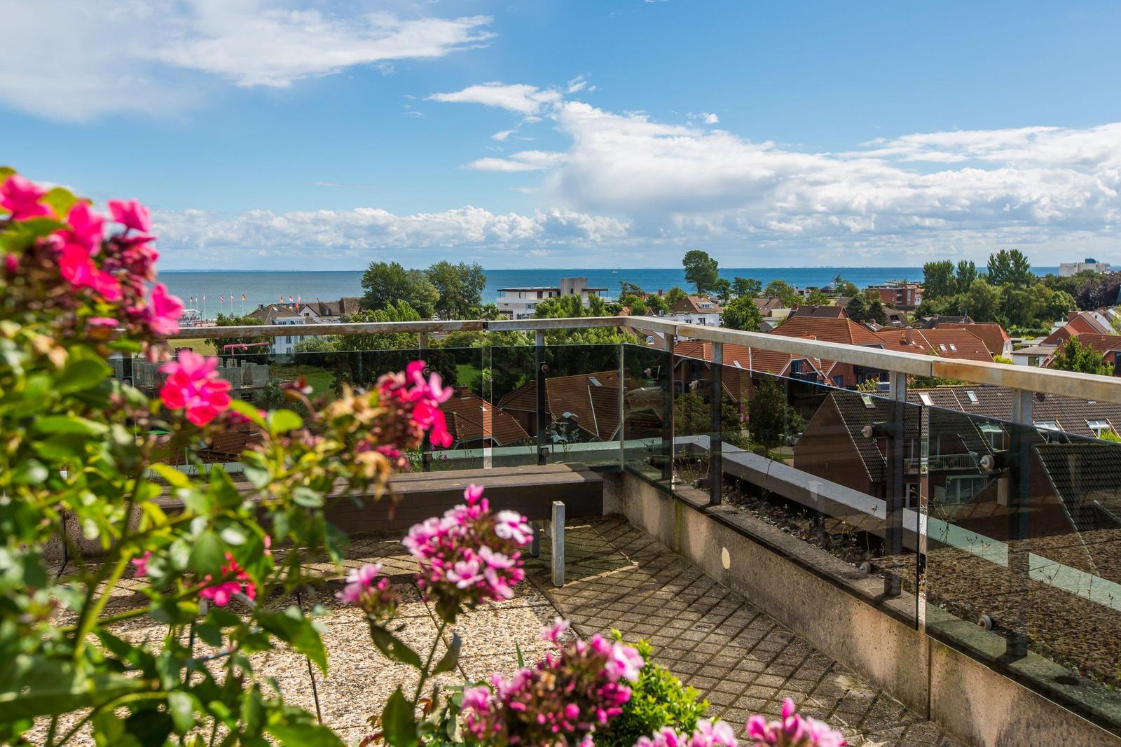 Rooftop-Garten mit Blumen und Blick auf die Stadt und das Meer.