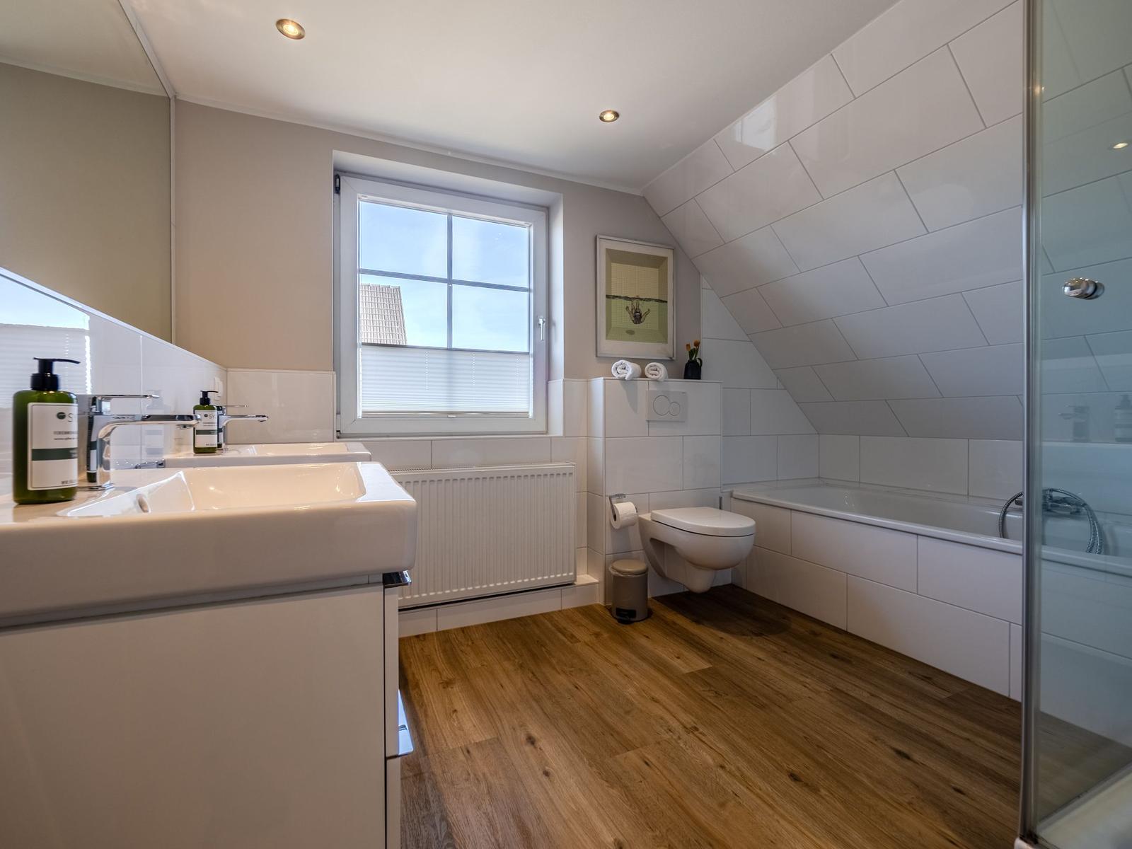 Badezimmer mit Badewanne, Dusche und Toilette unter schrägem Dach