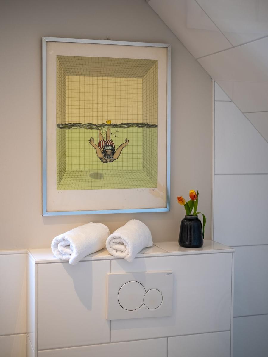 Ein Schlafzimmer mit Bett, Tisch und Fenster mit floralen Vorhängen.