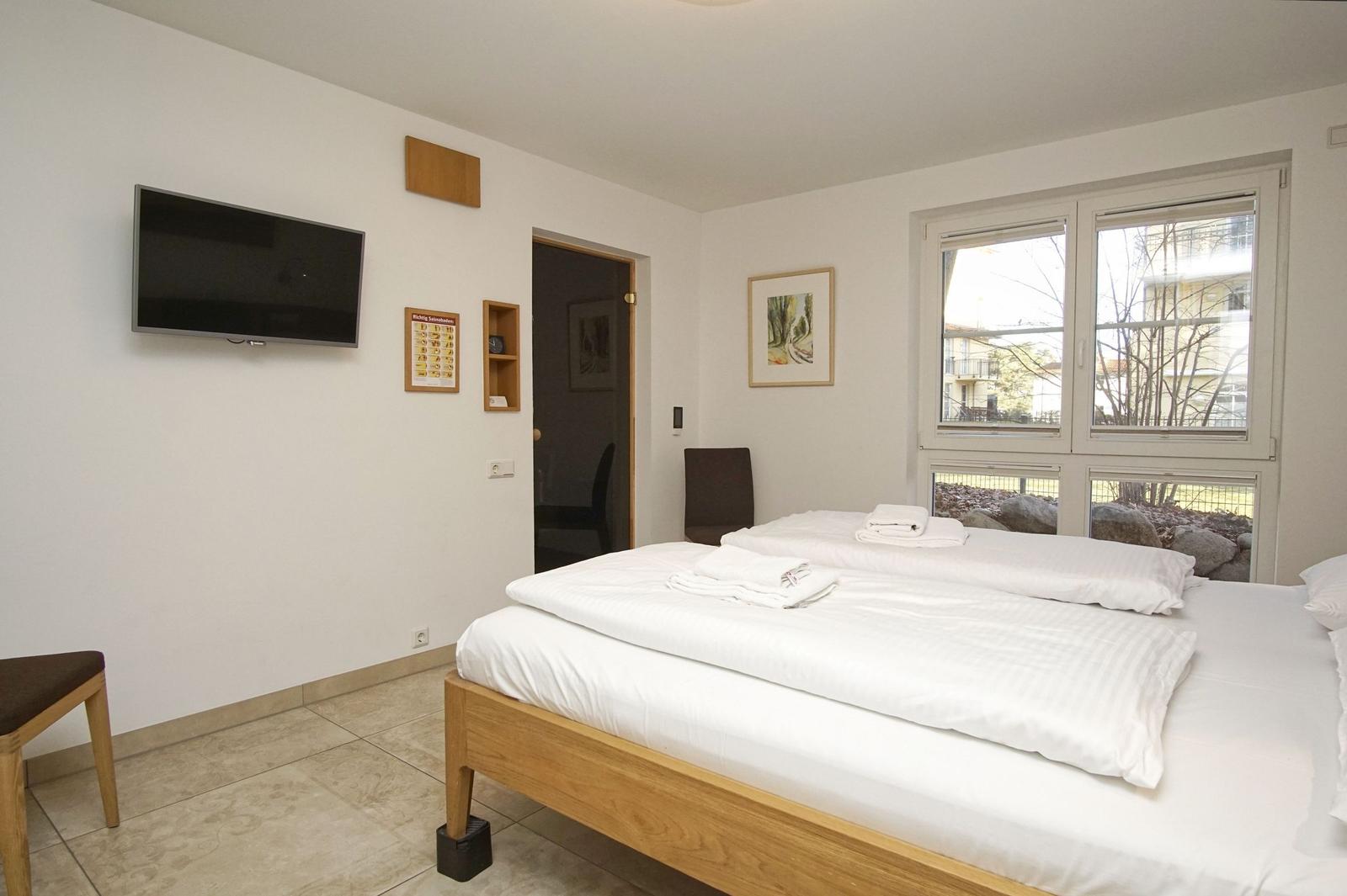 Schlafzimmer mit Bett, Stuhl und Fenster. Wandbilder und Beleuchtung.