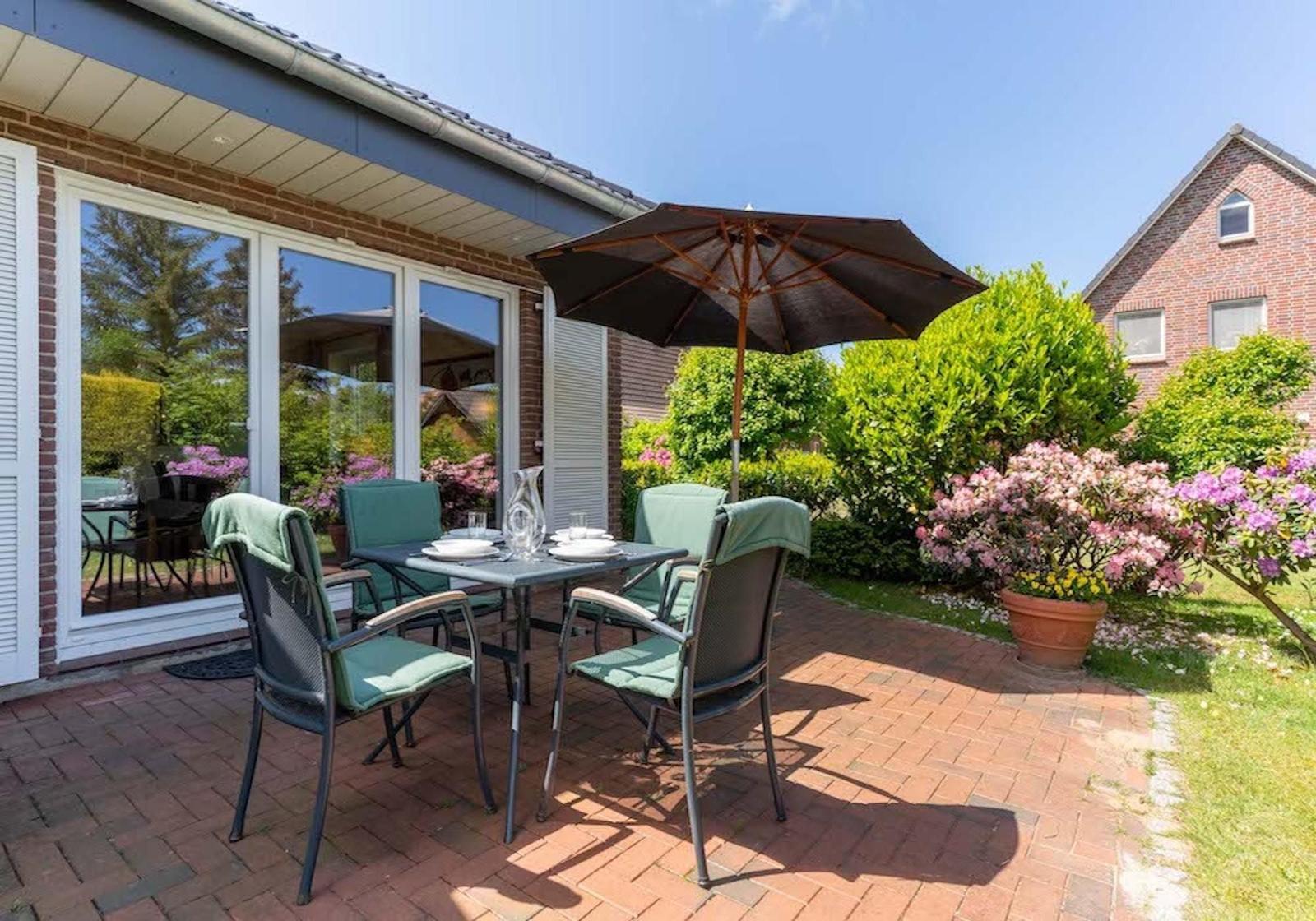 Living and dining area with wooden floor, sofa, chairs, and view of the garden.