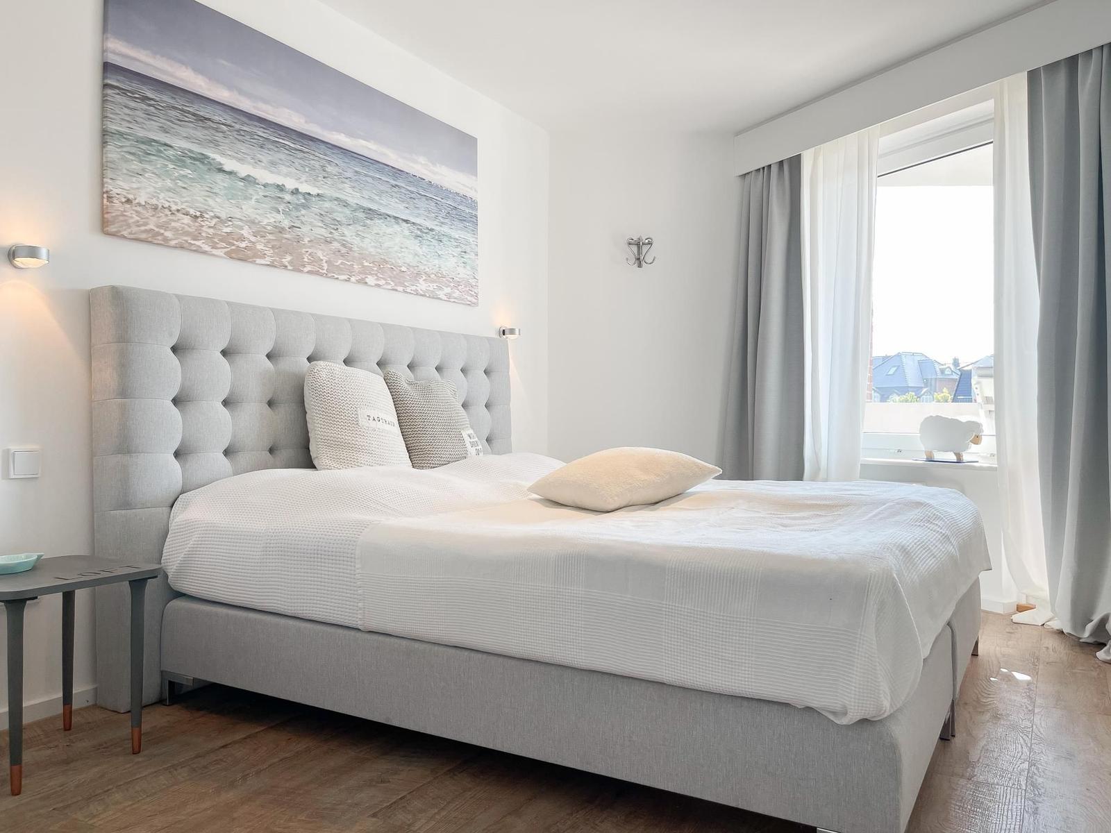 Schlafzimmer mit weißen Schränken und einem Spiegel mit Schnitzerei