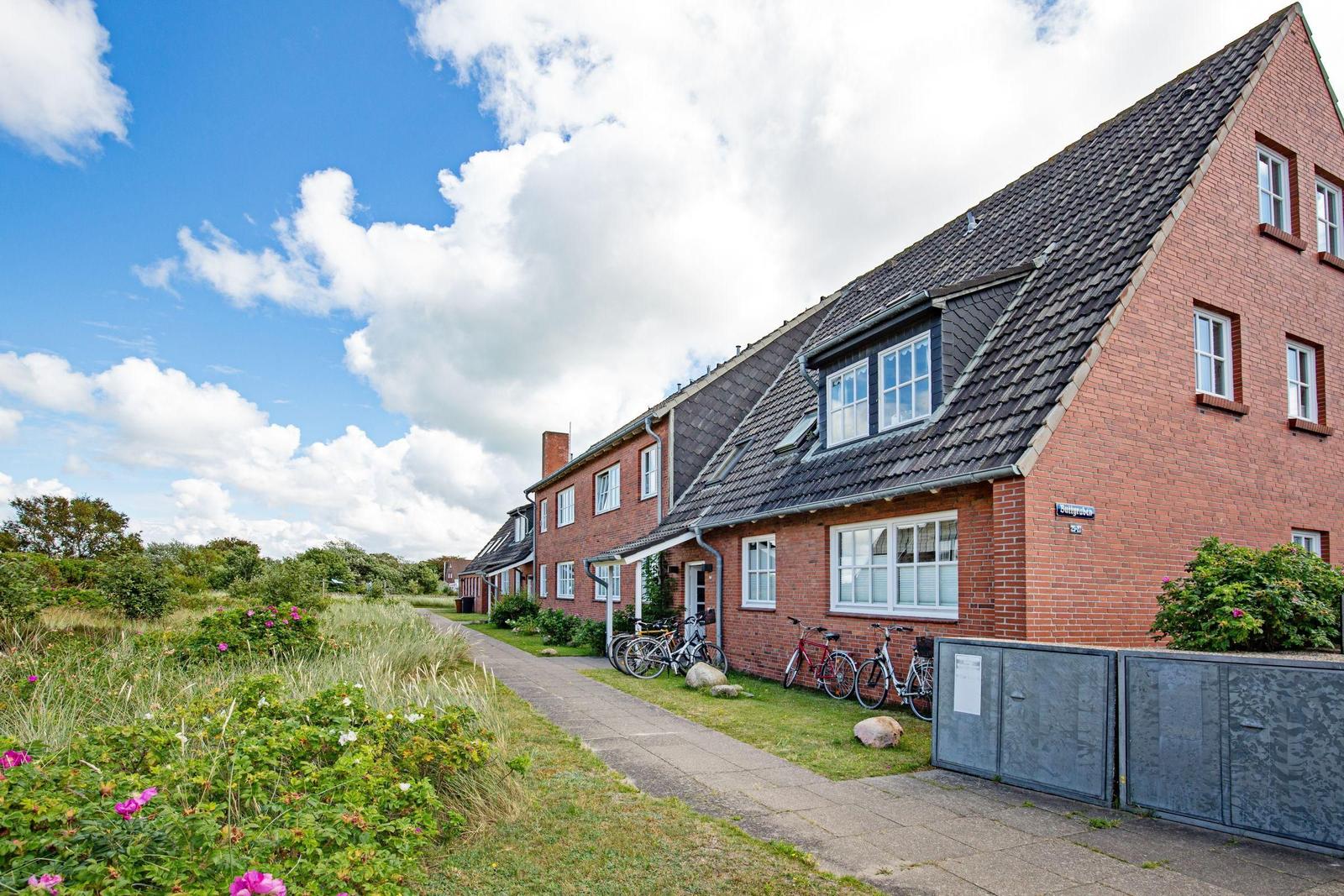 Haus mit Garten und Straße mit Autos. Steinmauern und Bäume umgeben die Grundstücke.