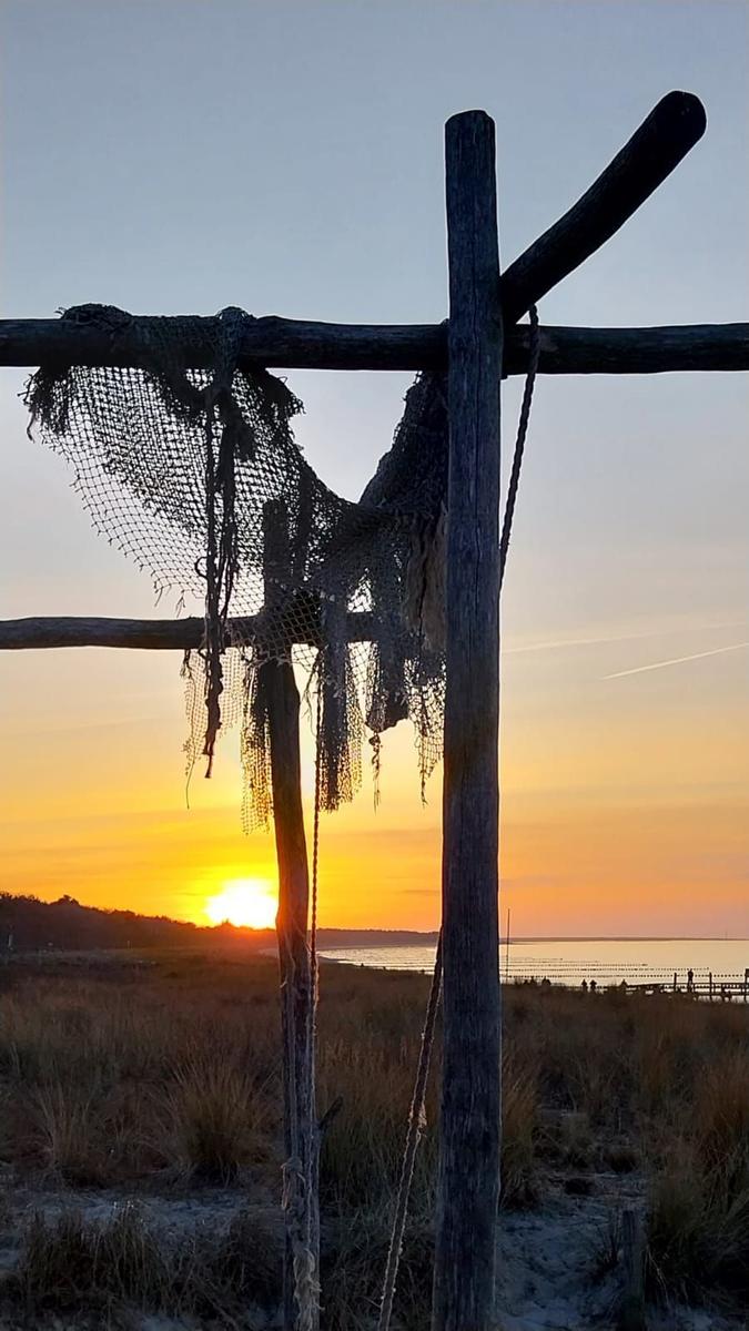 Sonnenuntergang am Strand mit Holzpfählen im Wasser