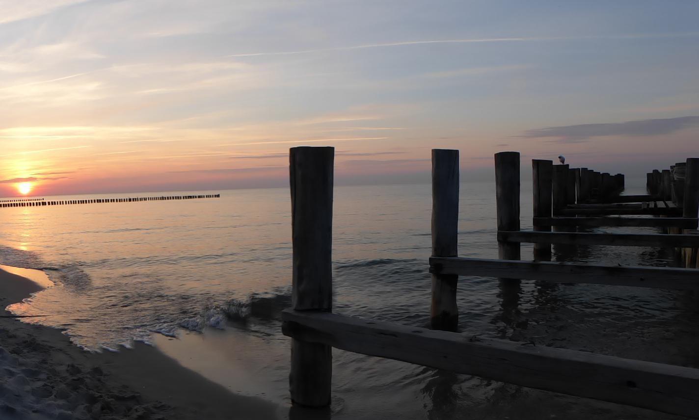 Strand mit Sanddünen und Wellen im Hintergrund.