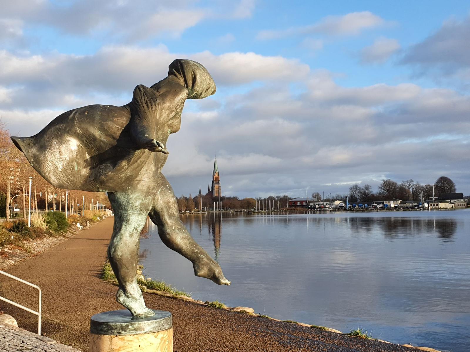 Hafen mit Booten und Steg. Im Hintergrund steht ein großes Gebäude.