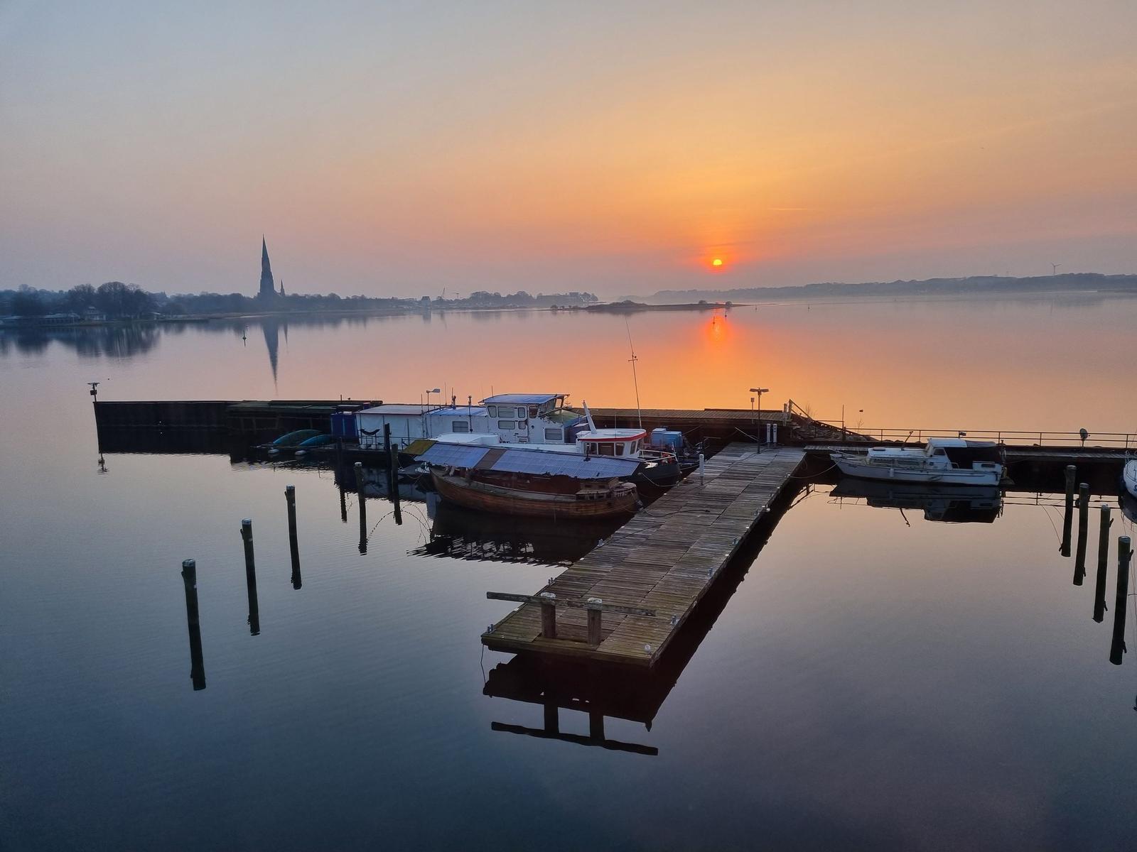 Sonnenuntergang über Hafen mit Booten und Spiegelung im Wasser