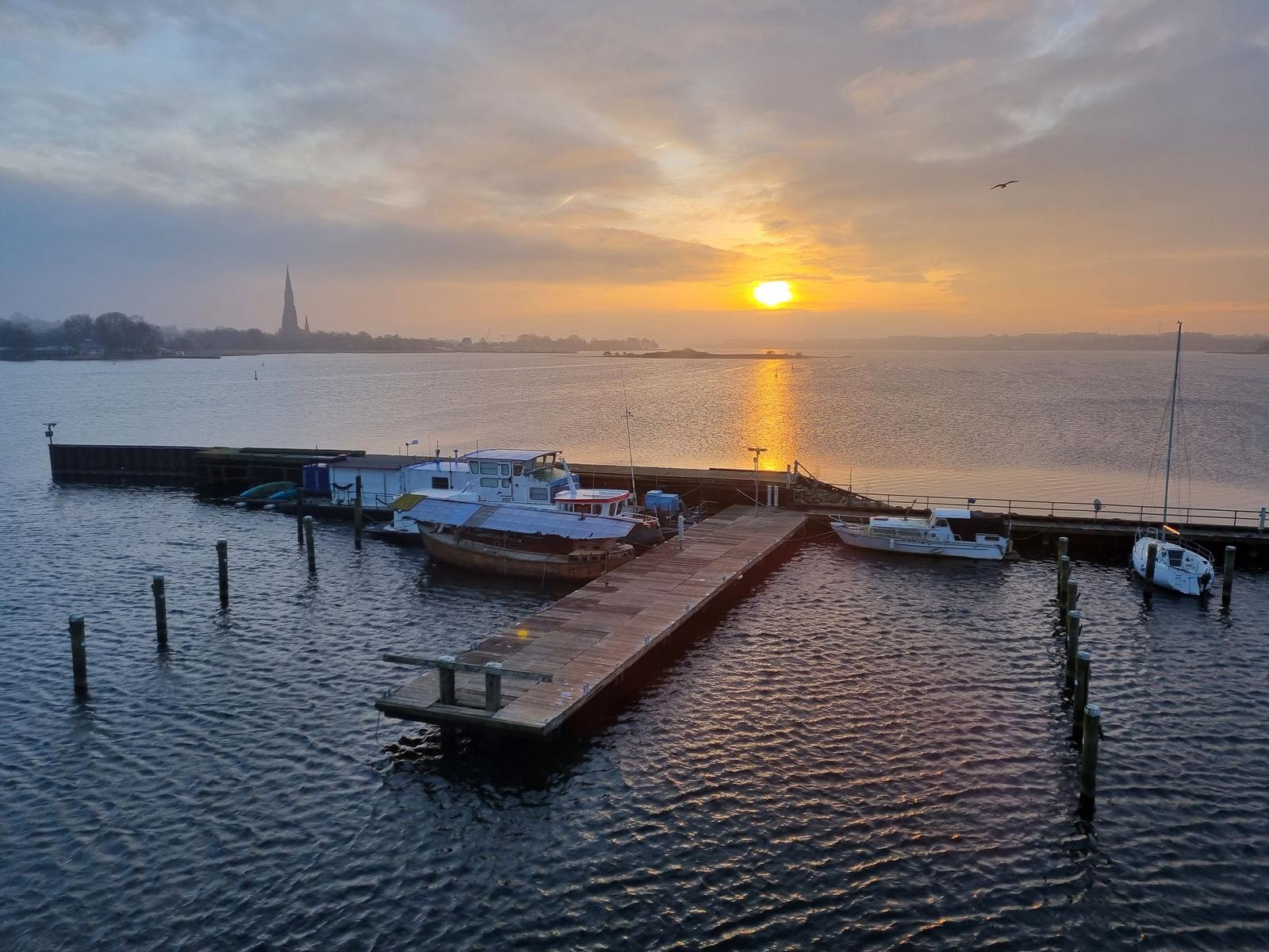 Hafen mit Booten und Stegen unter bewölktem Himmel.