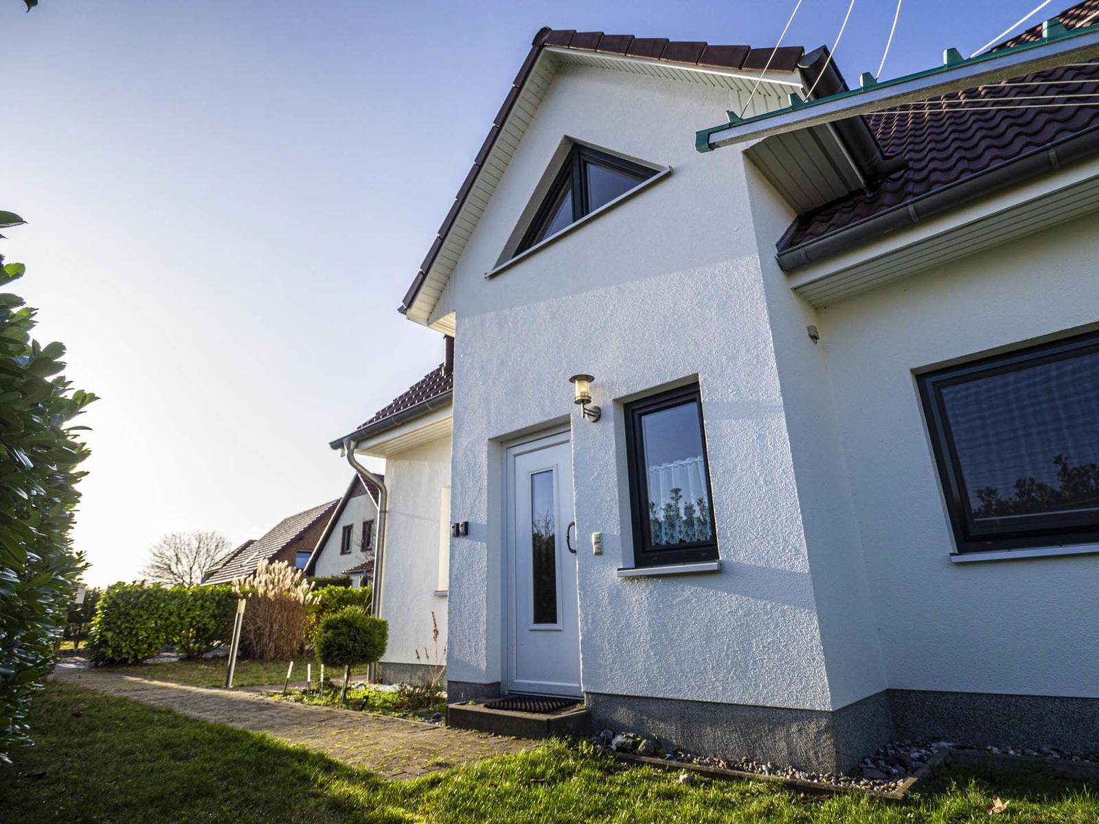 Wohnhaus mit Garten, Satellitenschüssel und Solaranlage im Hintergrund.