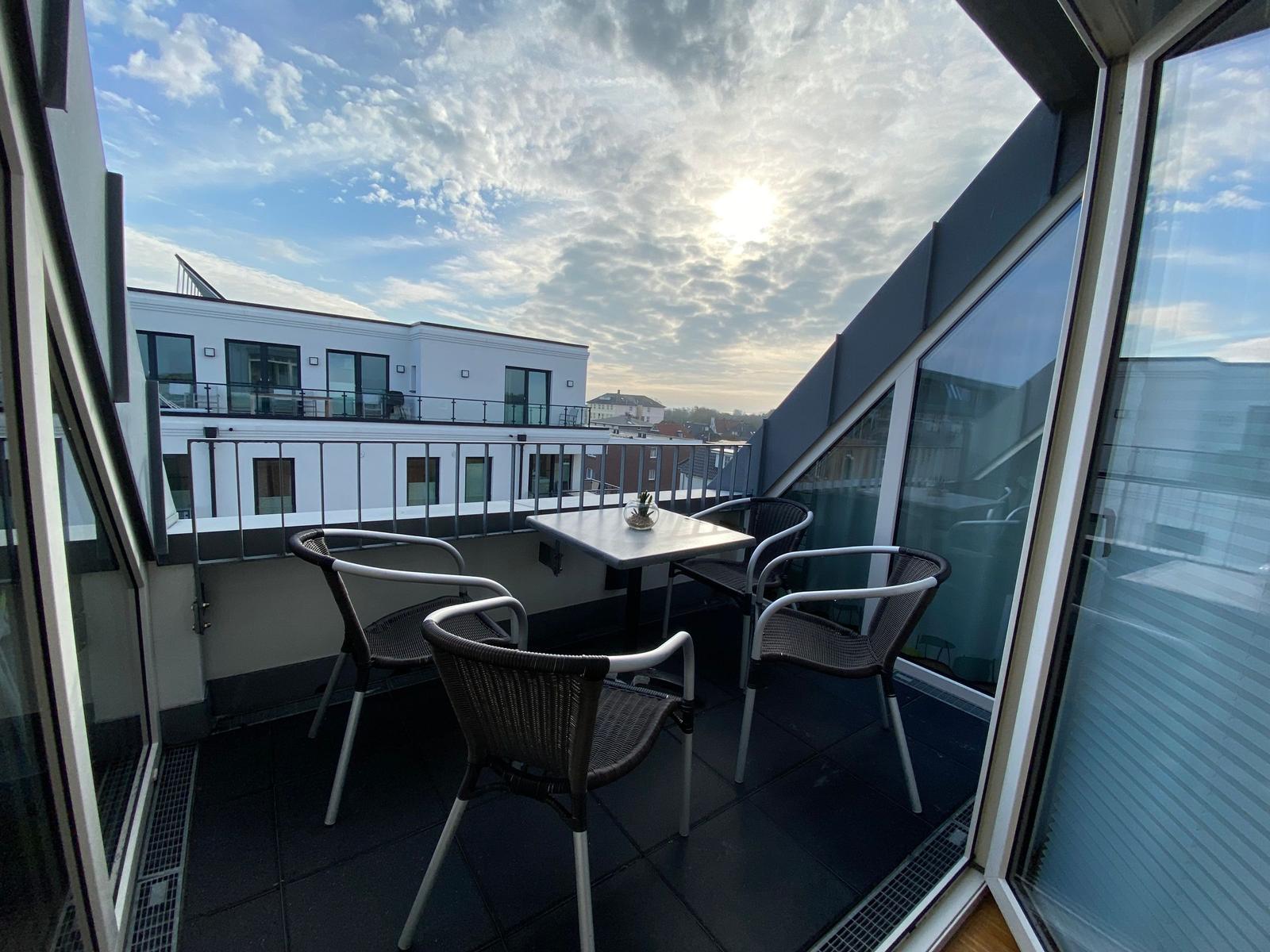 Terrasse mit Tisch und Stühlen, Blick auf Gebäude und Himmel