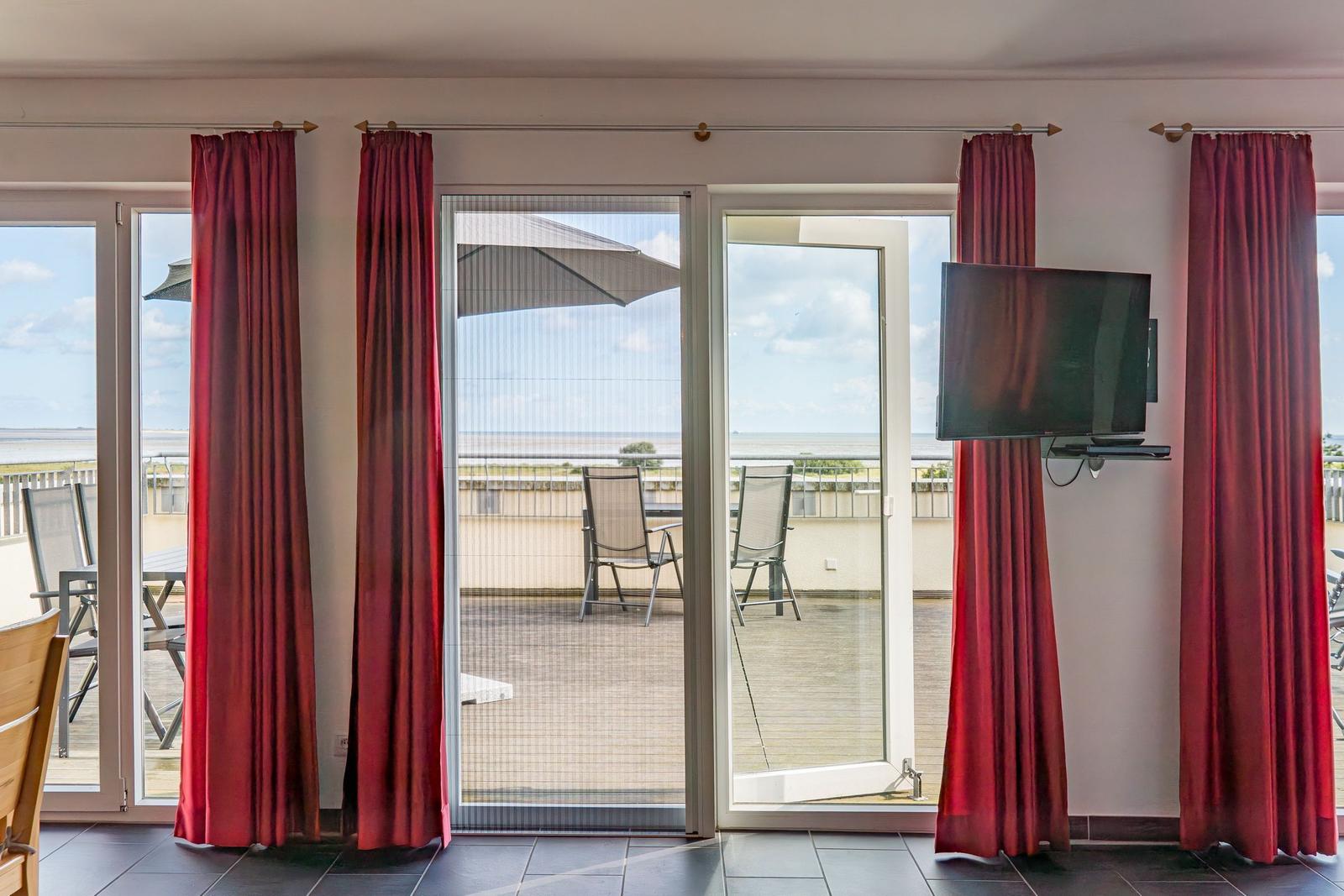 Terrasse mit Sonnenschirm, Liegestühlen und Tisch. Holzdielen und Balkon mit Blick.