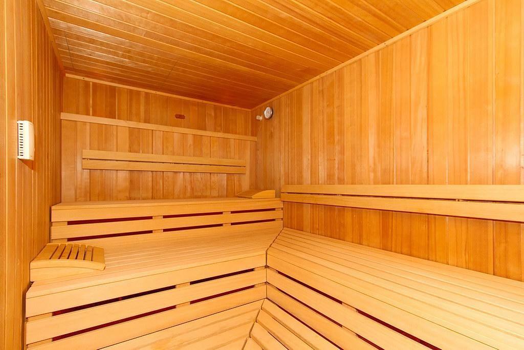 Sauna mit Holzbänken und Steinen im Kaminbereich