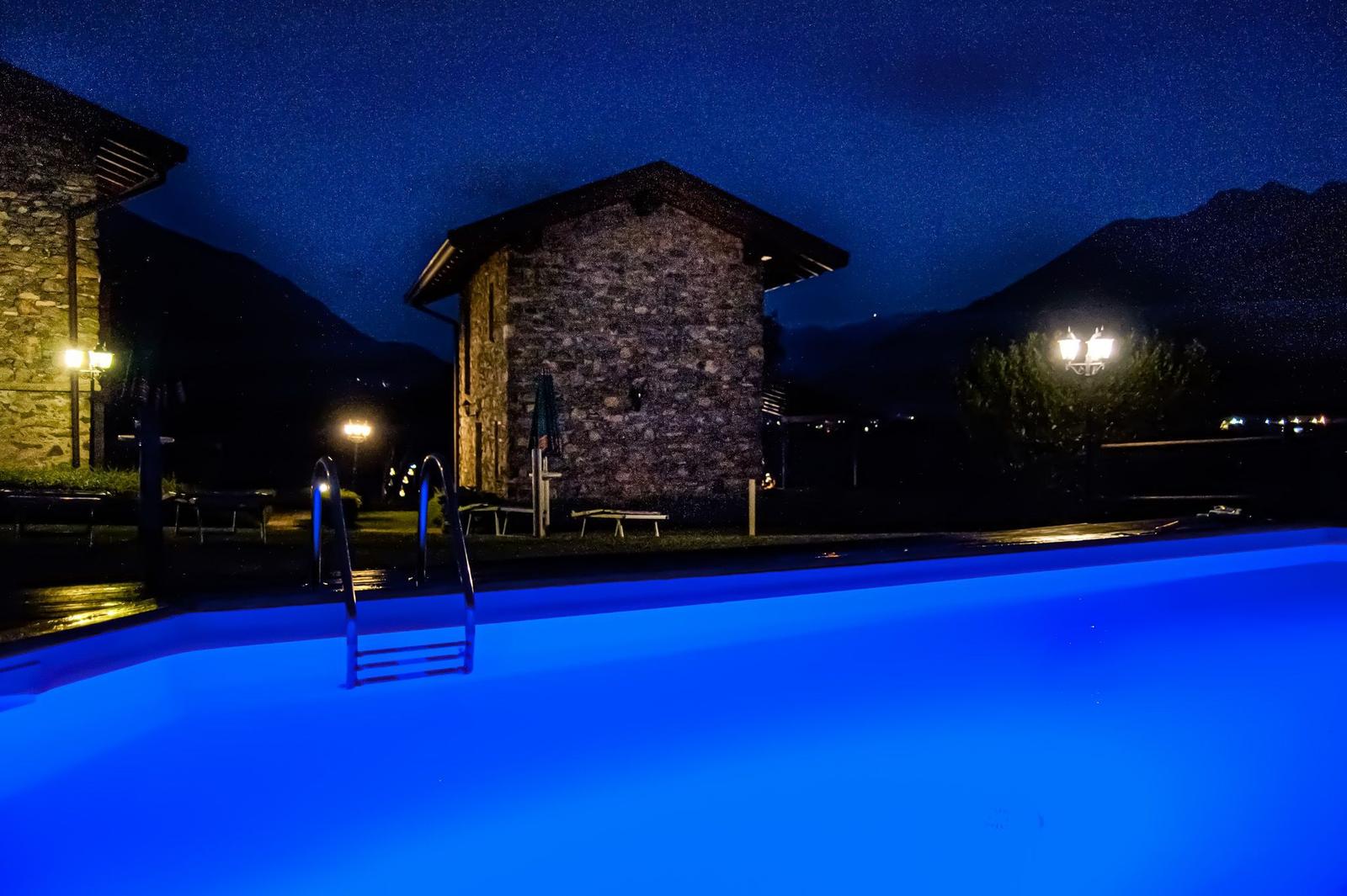 Landschaftsaufnahme von mehreren Steinwohnungen mit Pool und Garten bei Nacht.