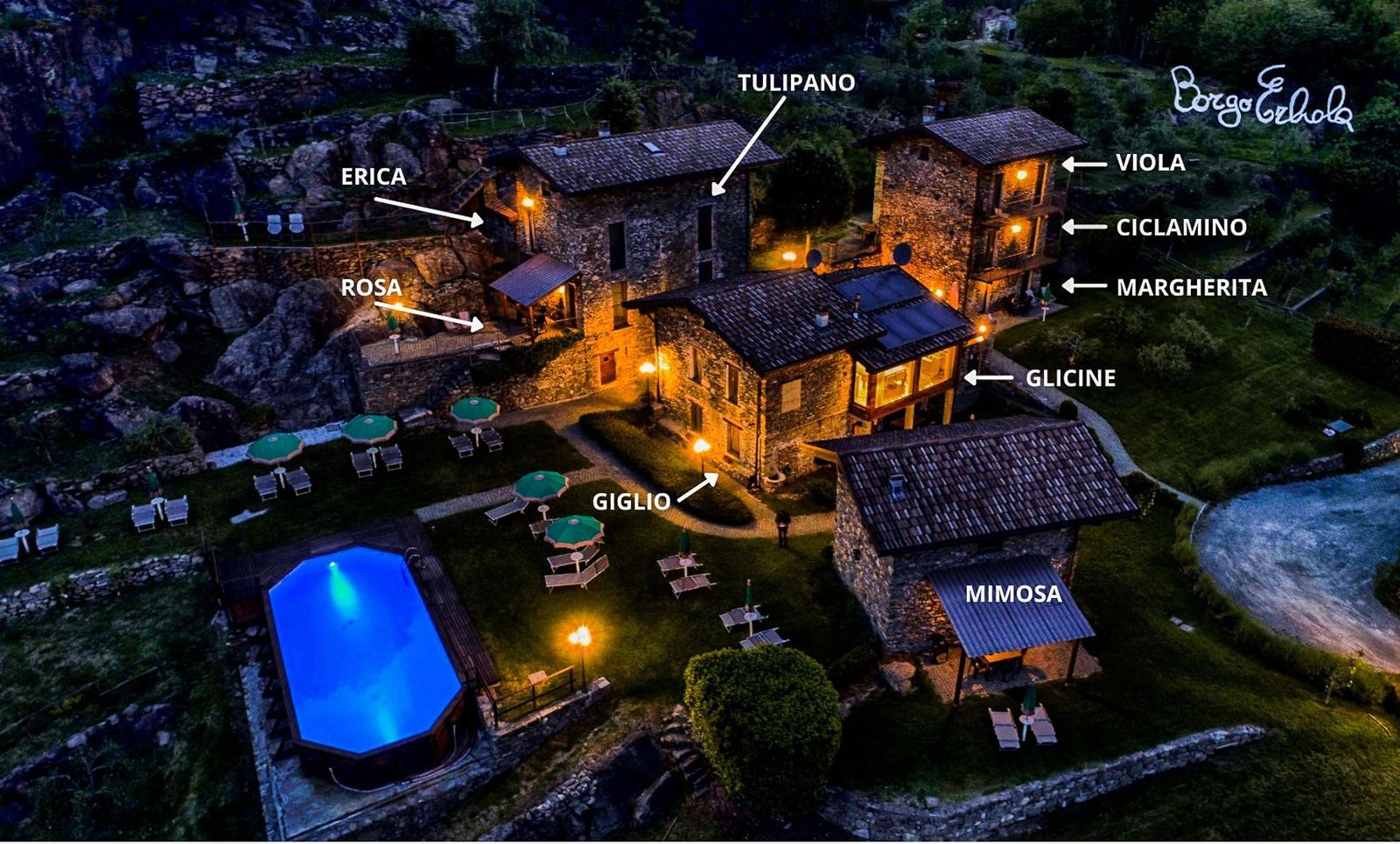 Beleuchteter Pool bei Nacht mit Blick auf Berg und Stadtlichter.