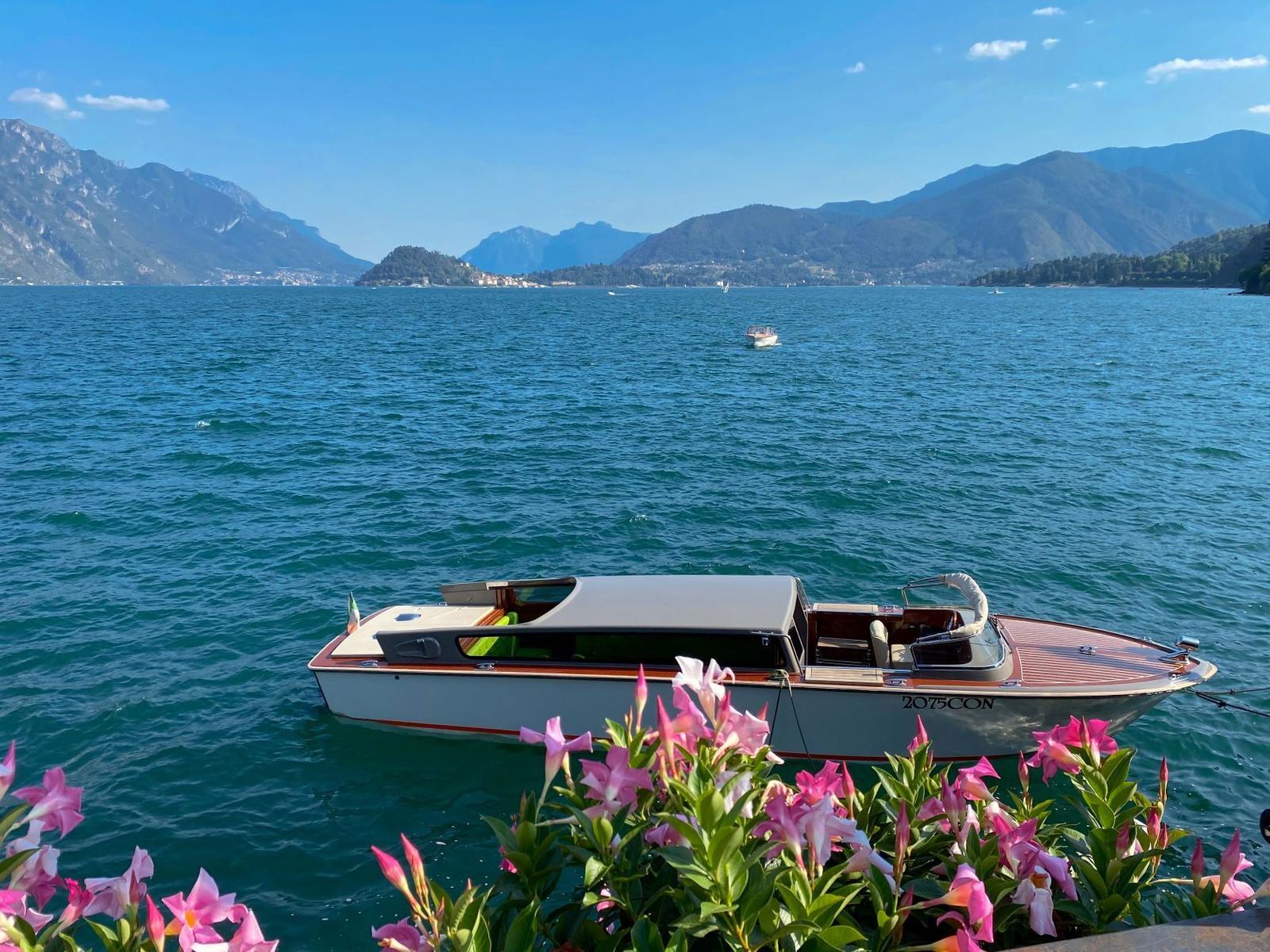 Hafen mit Booten, Flaggen und blühenden Pflanzen vor Berglandschaft