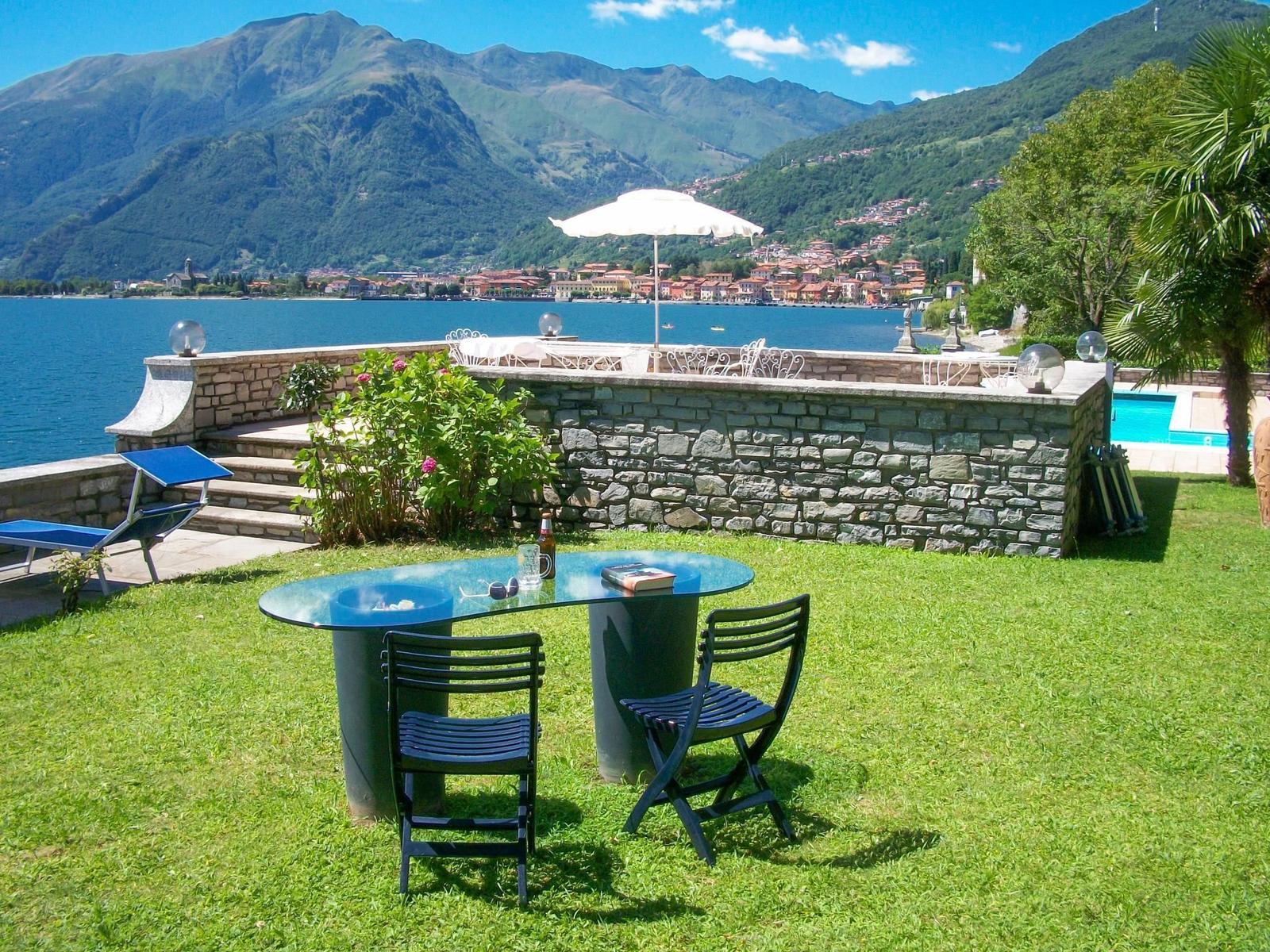 Pool mit Liegestühlen und Blick auf See und Berge.