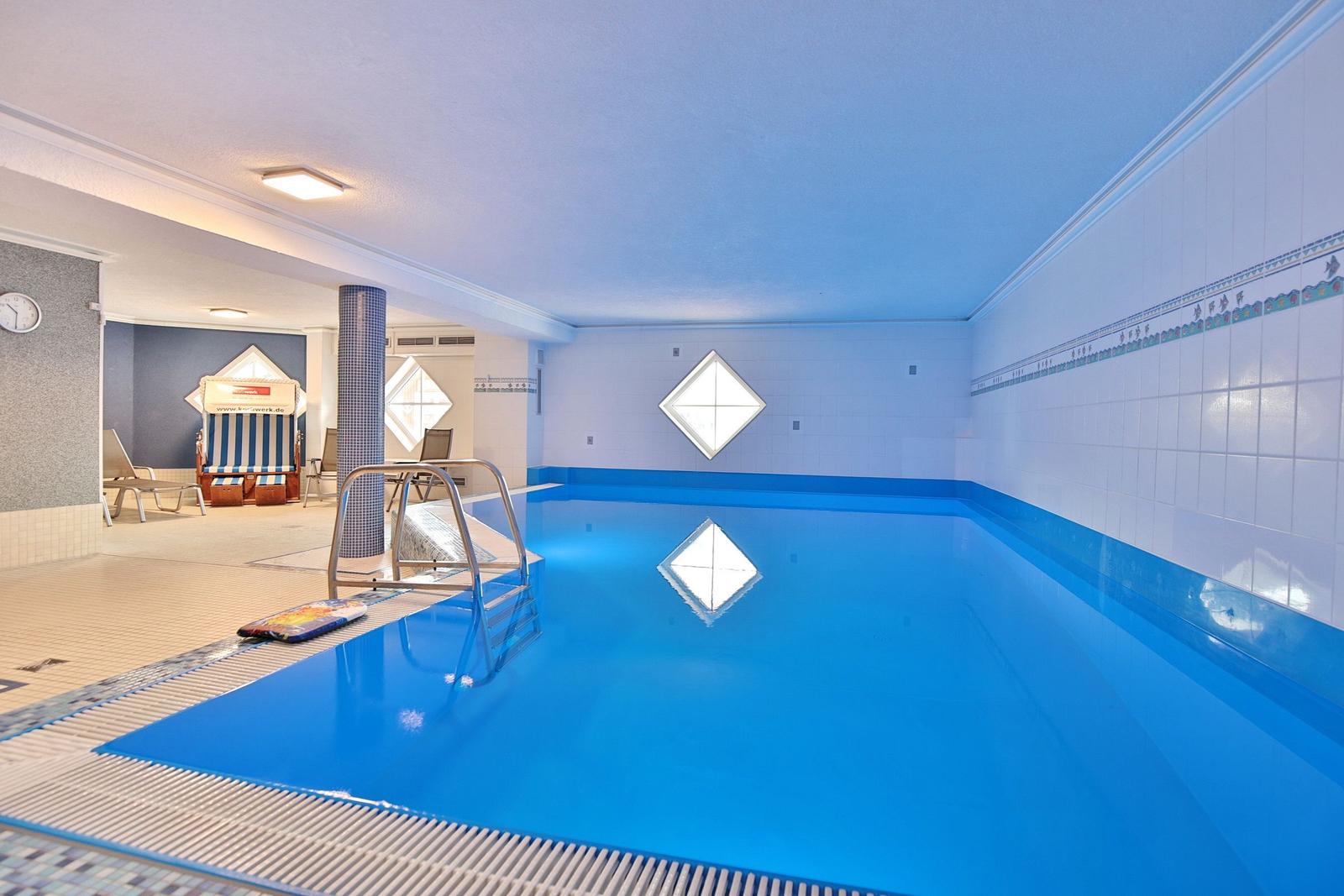 Innere Schwimmhalle mit Pool, Dusche und Bodenfliesen.