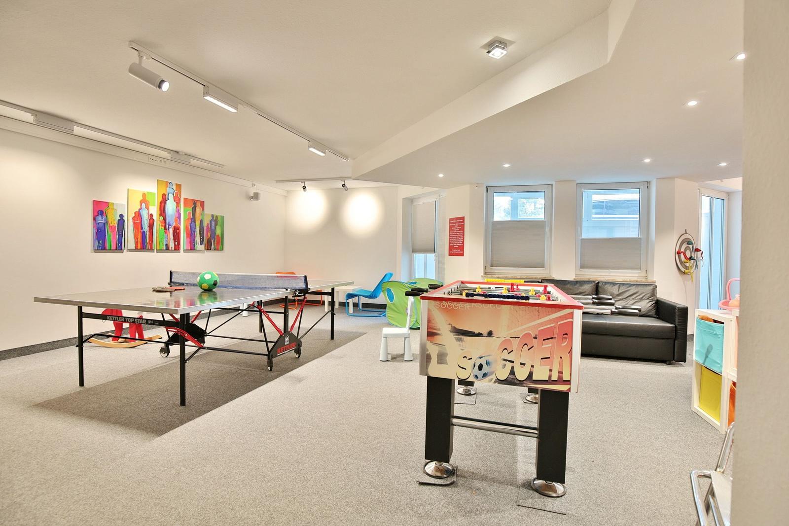 Ein Raum mit orangefarbenem Sofa, Spielzeug und einem Tisch mit Stühlen.