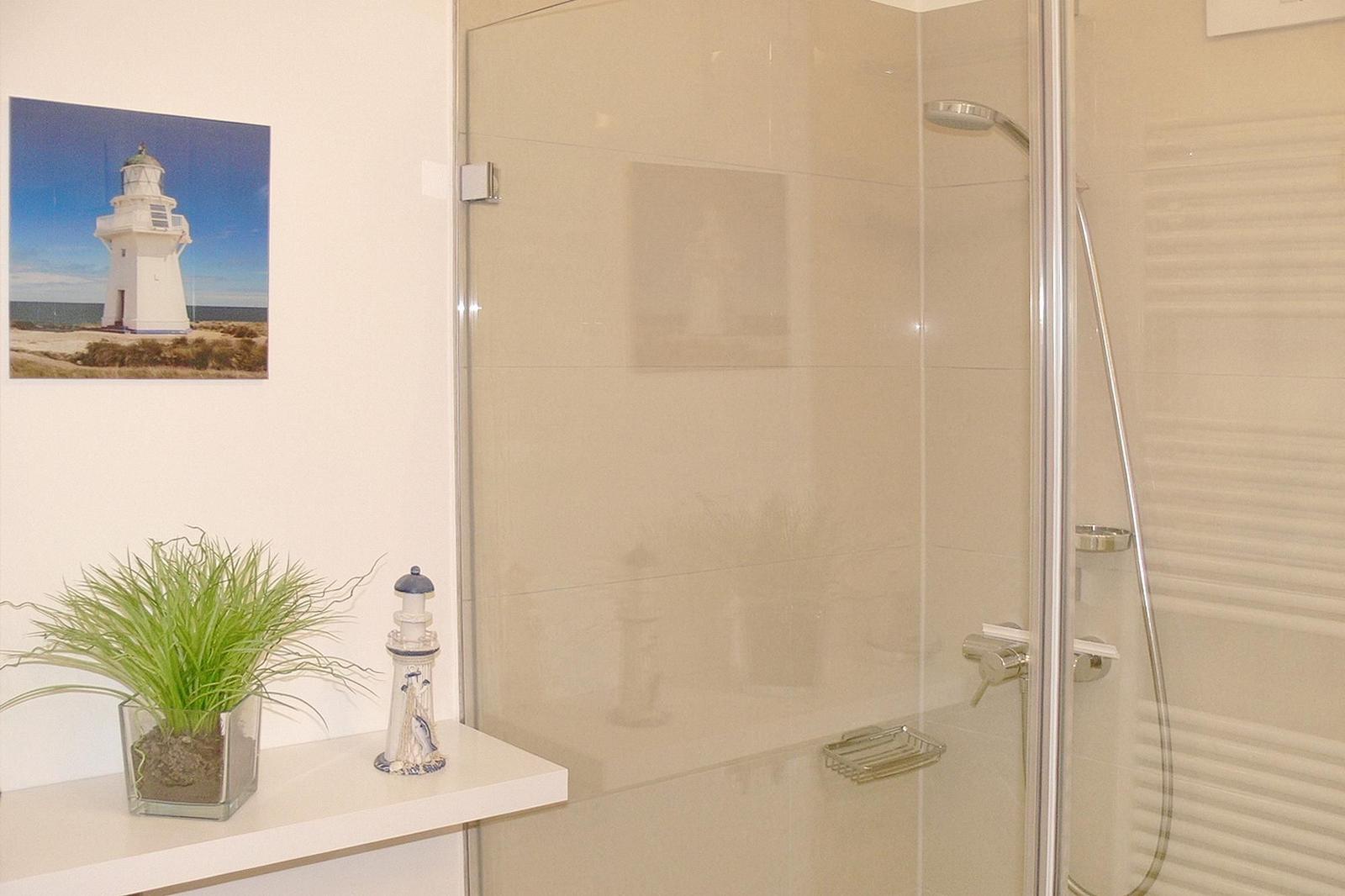 Bad mit Dusche, Heizkörper und Wandbild mit Segelyacht.
