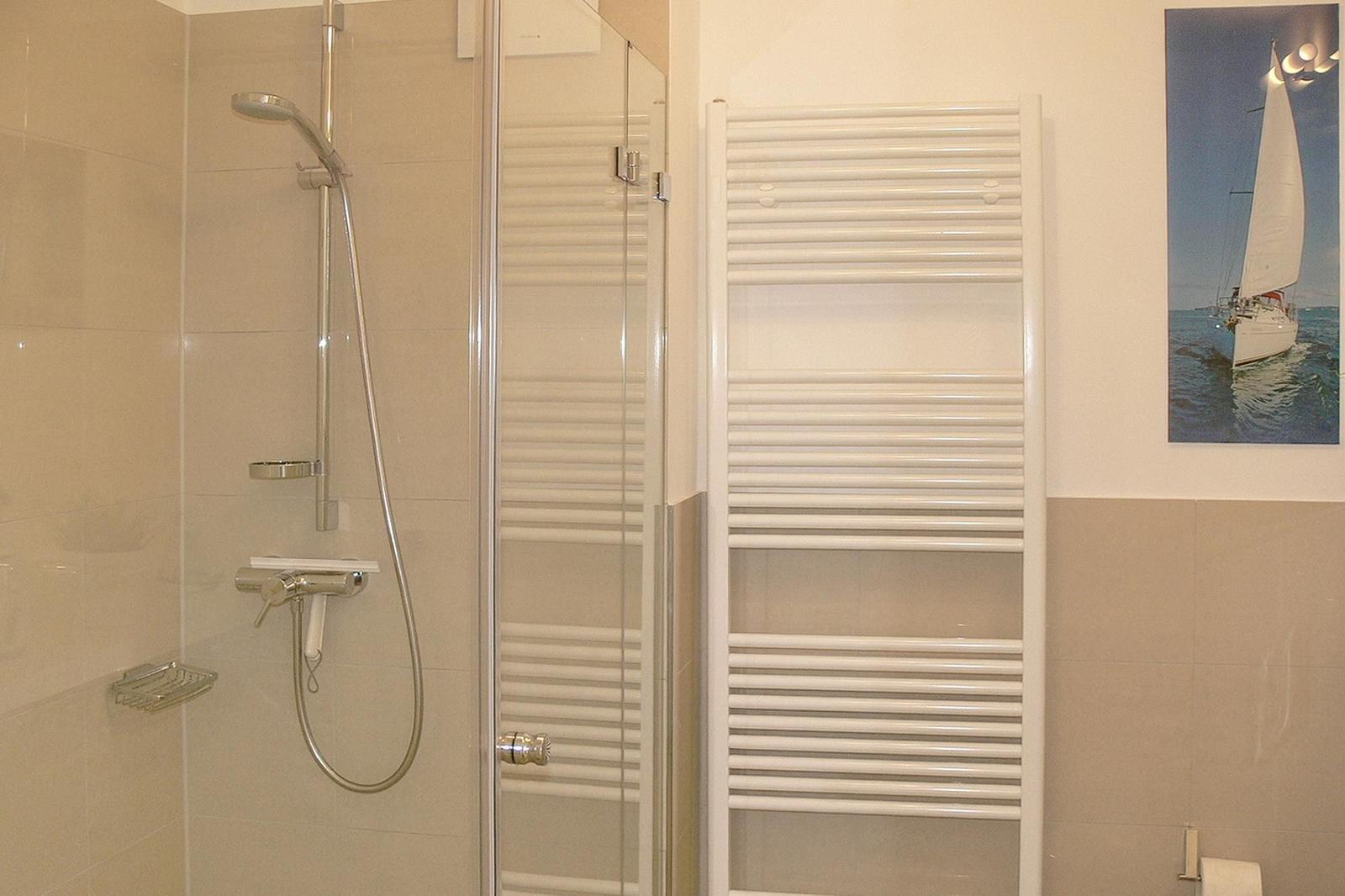 Badezimmer mit Spiegel, Handtuchhalter und Haartrockner an der Wand.