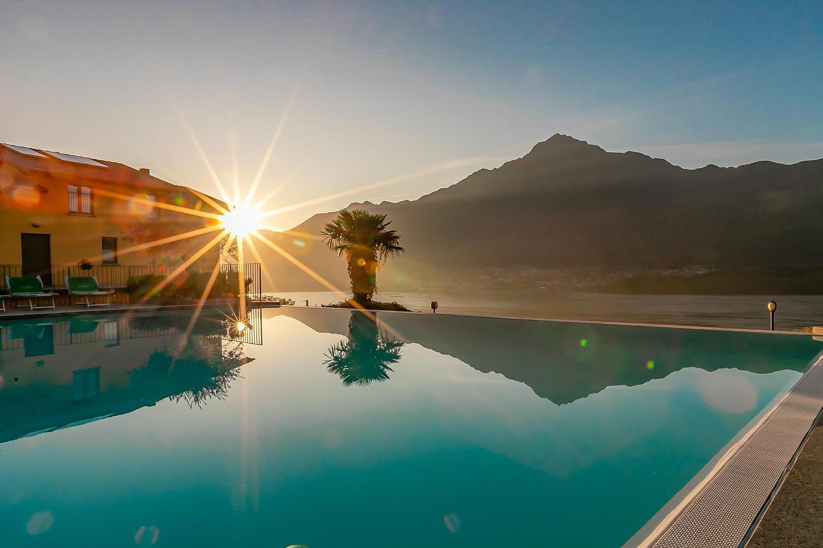 Pool mit Blick auf See und Berge bei Sonnenuntergang.