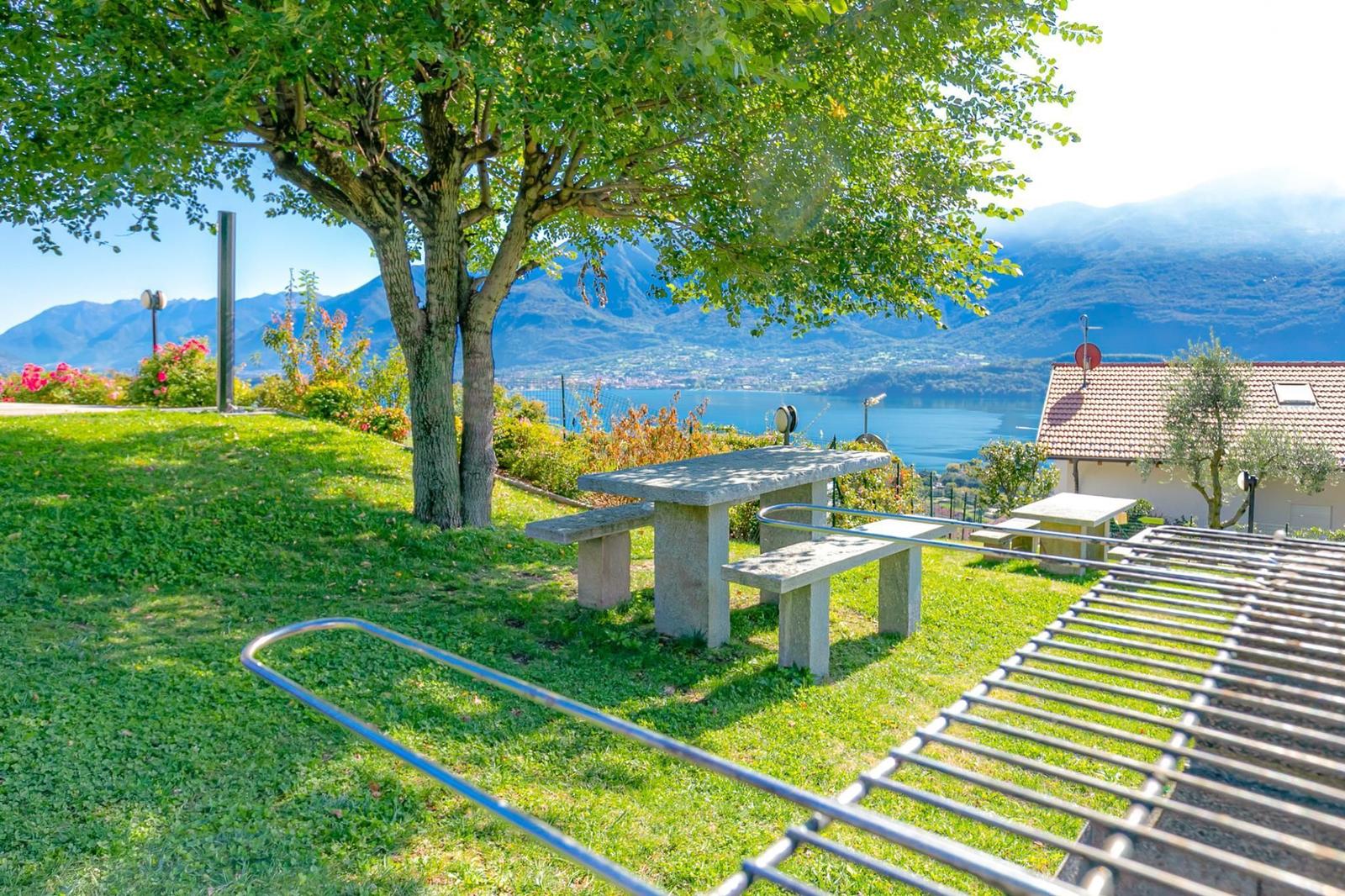 Holzspielplatz mit Rutsche und Schaukel, Sonne scheint durch Dach, Blick auf See und Berge.