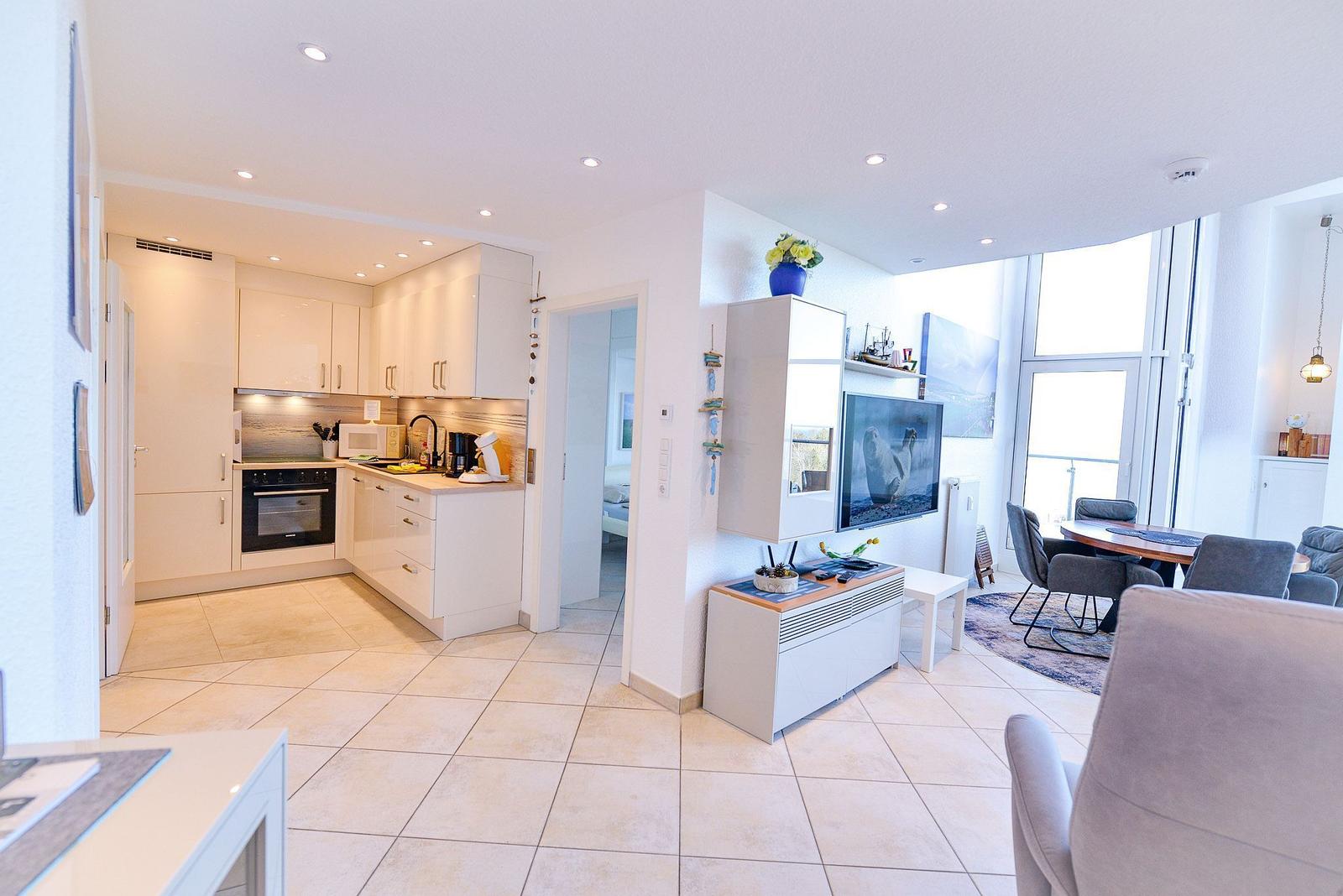 Wohnung mit Küche, Schlafzimmer, Bad und Terrasse mit Sitzgelegenheiten.