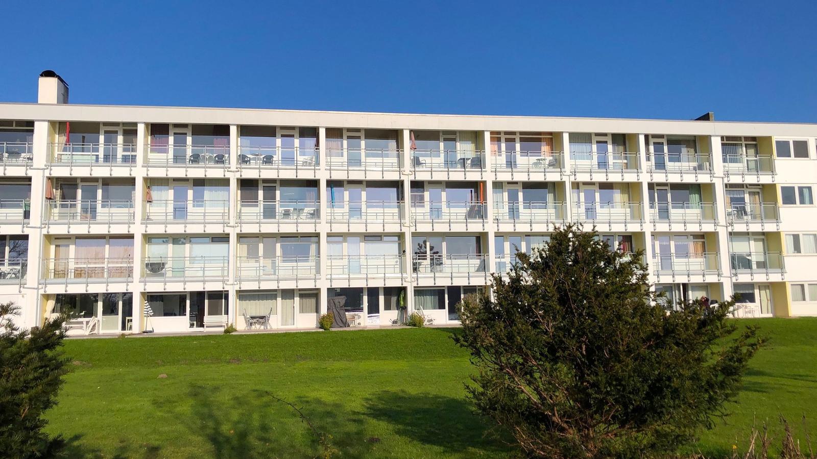 Wohnung mit Doppelbett, Sofa, Küche, Bad und Balkon.