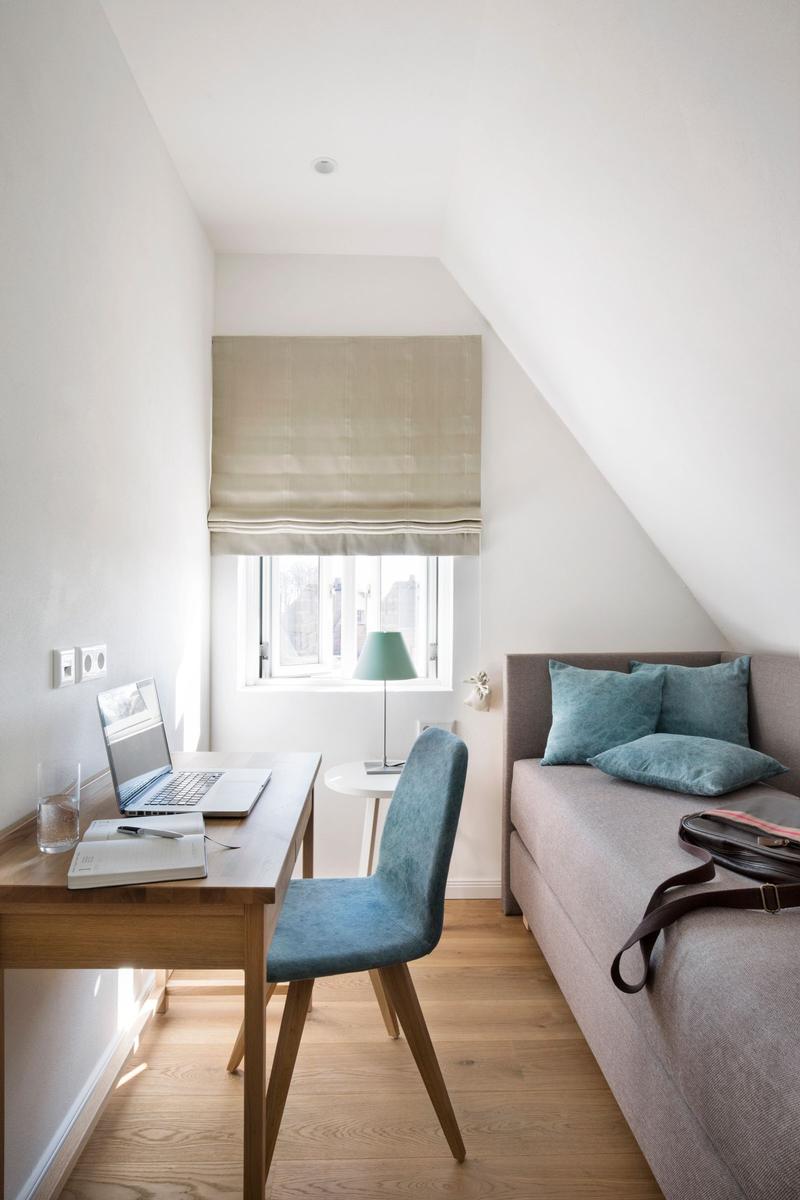 Schlafzimmer mit Bett, Schrank, Schreibtisch und Fernseher an der Wand.