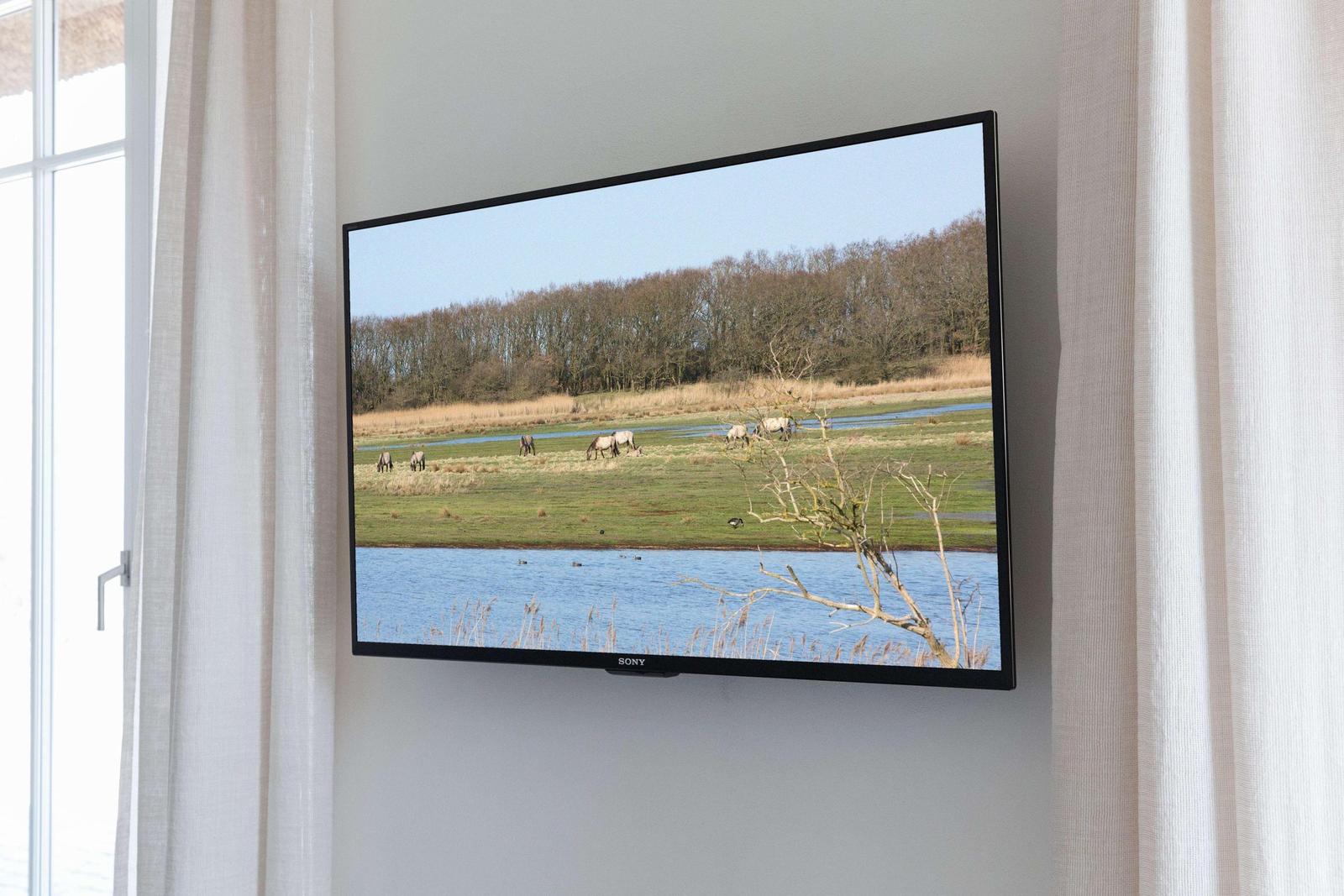 Schlafzimmer mit Bett, weißen Bettwäsche und gelben Kissen. Holzfußboden und Fenster mit Vorhängen.