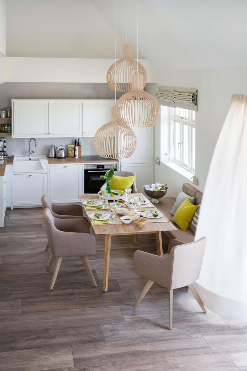 Wohnzimmer mit Sofa, gelben Kissen, zwei hängenden Lampen und großem Fenster.