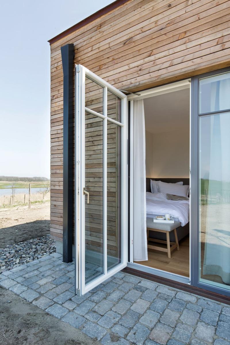 Schlafzimmer mit Bett, Holzfußboden und Fenster mit Vorhängen.