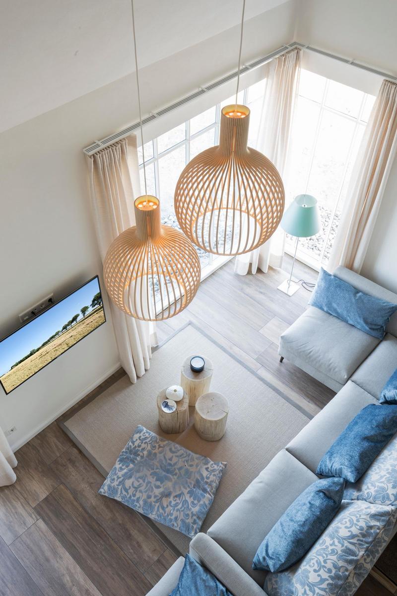 Ein Schlafzimmer mit Bett, Nachttisch und Lampe. Holzboden und Fenster mit Vorhängen.