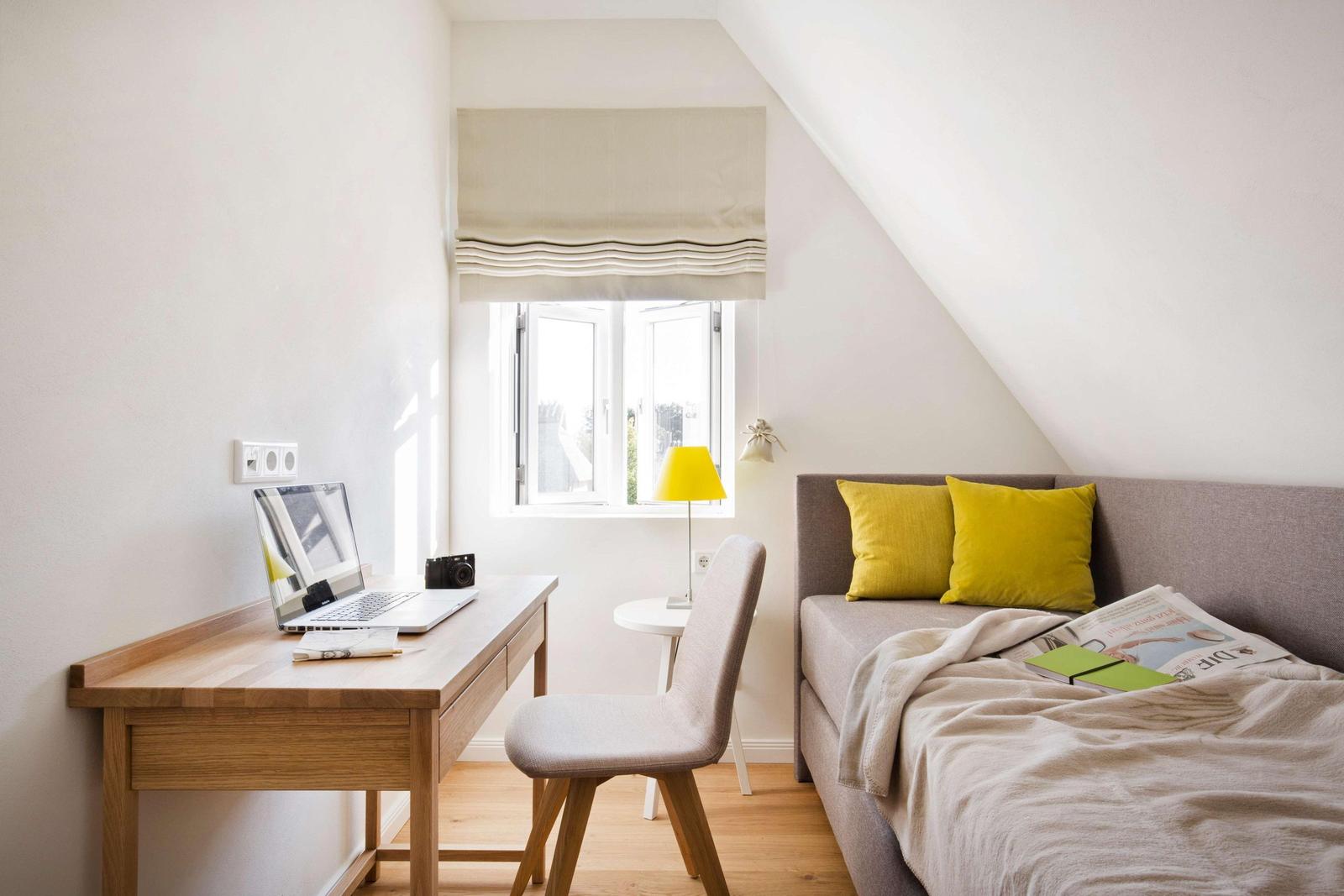 Schlafzimmer mit Bett, Kissen, Decke, Bank und Koffer.