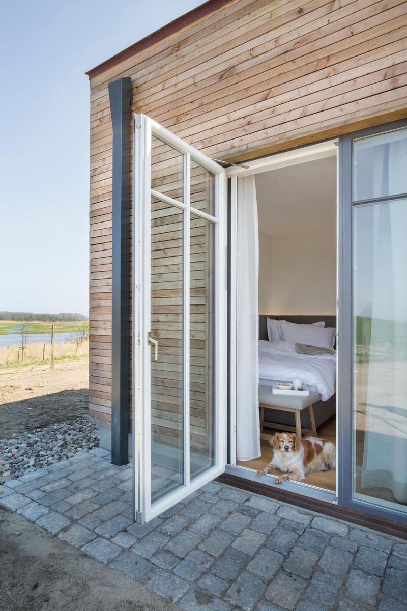 Sauna mit Holztür und Thermostat. Nebenraum mit Holztisch, Badematten und Fenster.