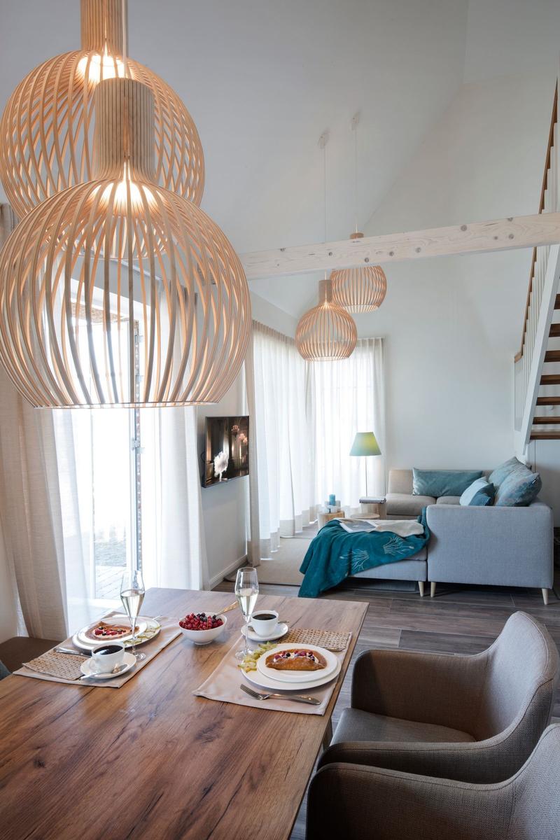 Ein Bett mit grünem Decken und Kissen. Ein alter Koffer steht auf einem Hocker.