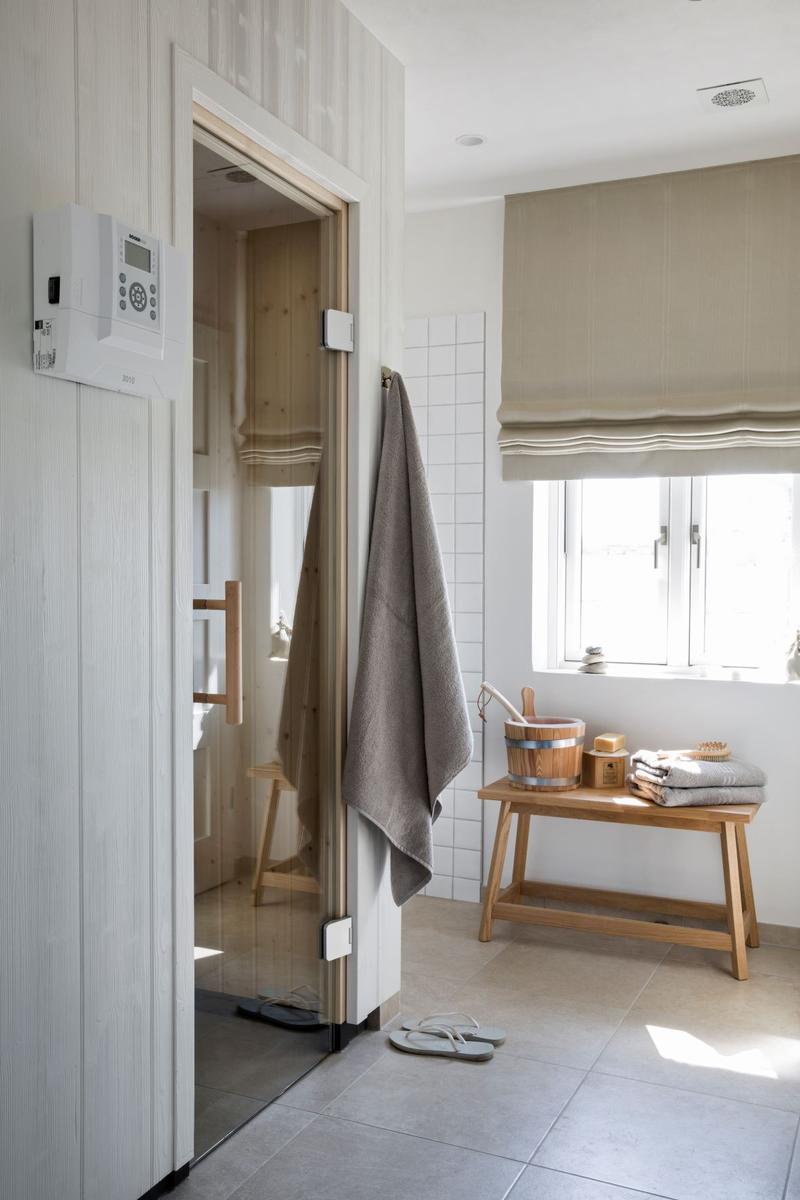 Badewanne mit grünem Wasser, weißer Fliesenwand und Duschkopf.