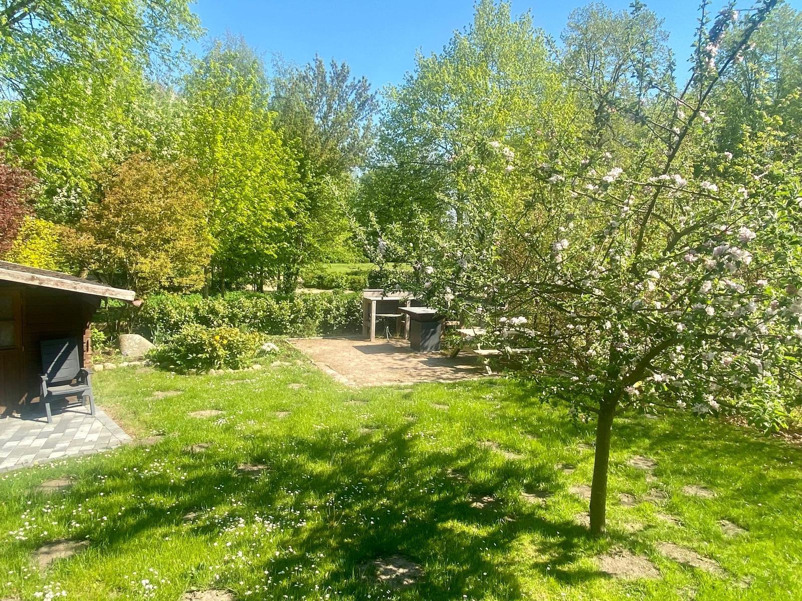 Terrasse mit Stein und Geländer, Blick in grünen Garten mit Picknicktisch.