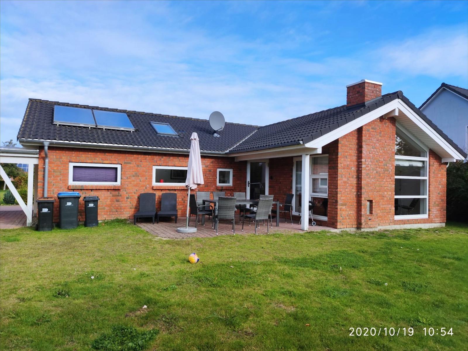 Red brick house with terrace, garden, and sun loungers. Backyard with shed and trees.