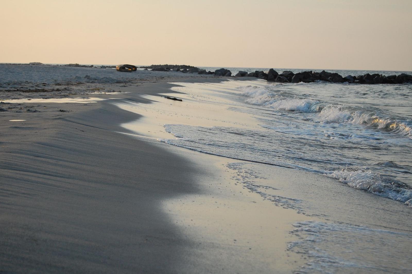 Strandkörbe mit Nummern stehen auf sandigem Strand bei Sonnenuntergang.