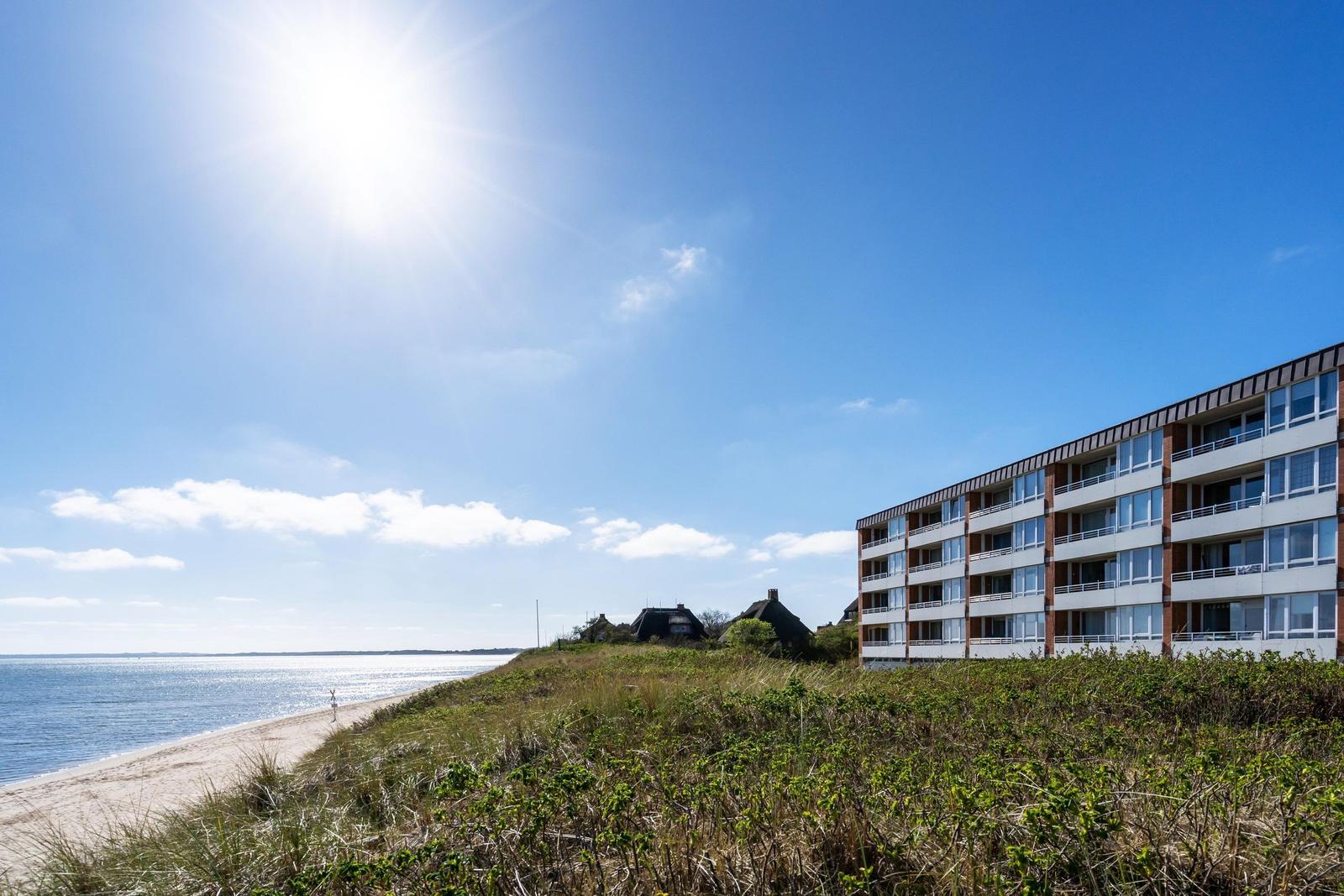 Strand mit Strandkörben und Sanddünen im Hintergrund.