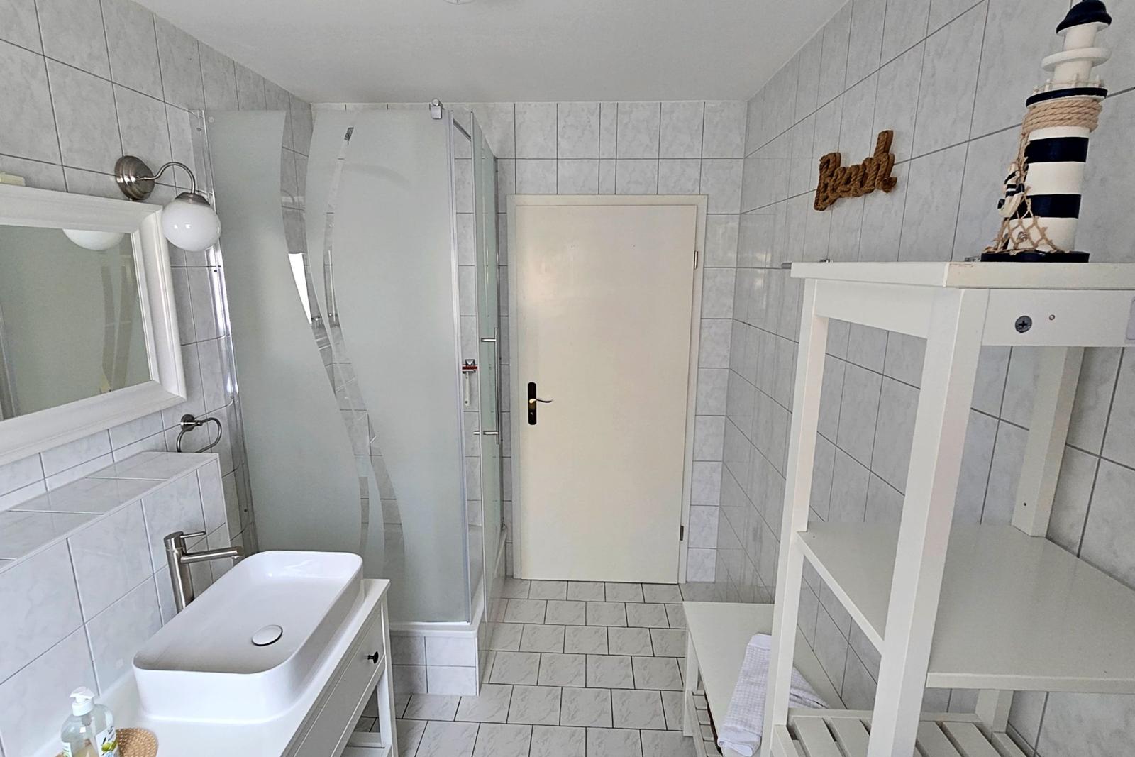 Weiß gefliestes Badezimmer mit Dusche und Fenster für reichlich Tageslicht