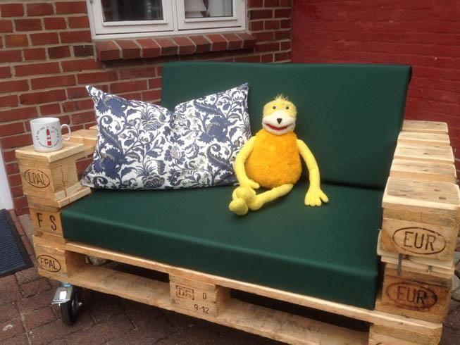 Holzüberdachter Außenbereich mit Grill, Tisch und Blick auf einen Garten.